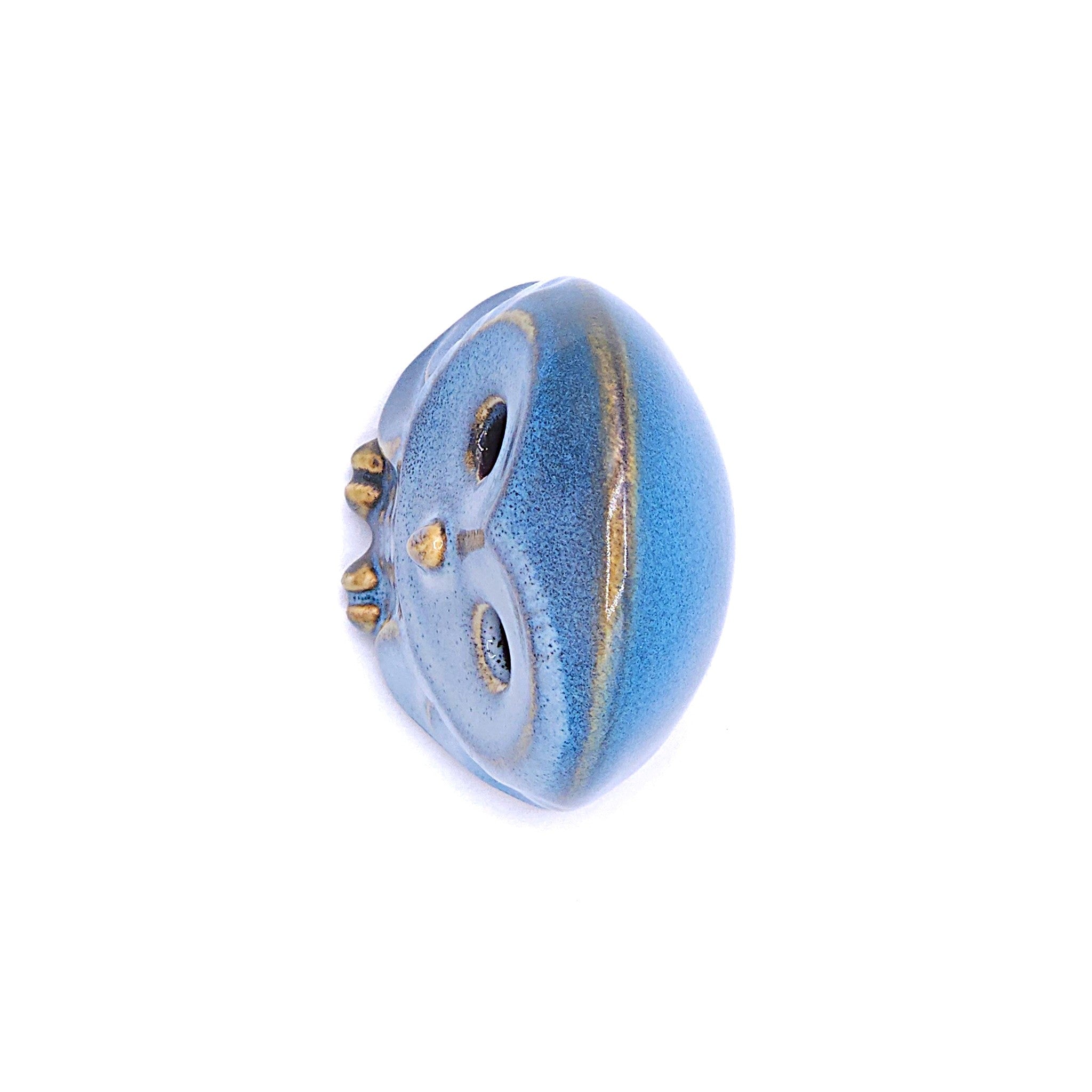 A top view of a handcrafted ceramic figurine of an owl with a blue. Tsukushi
