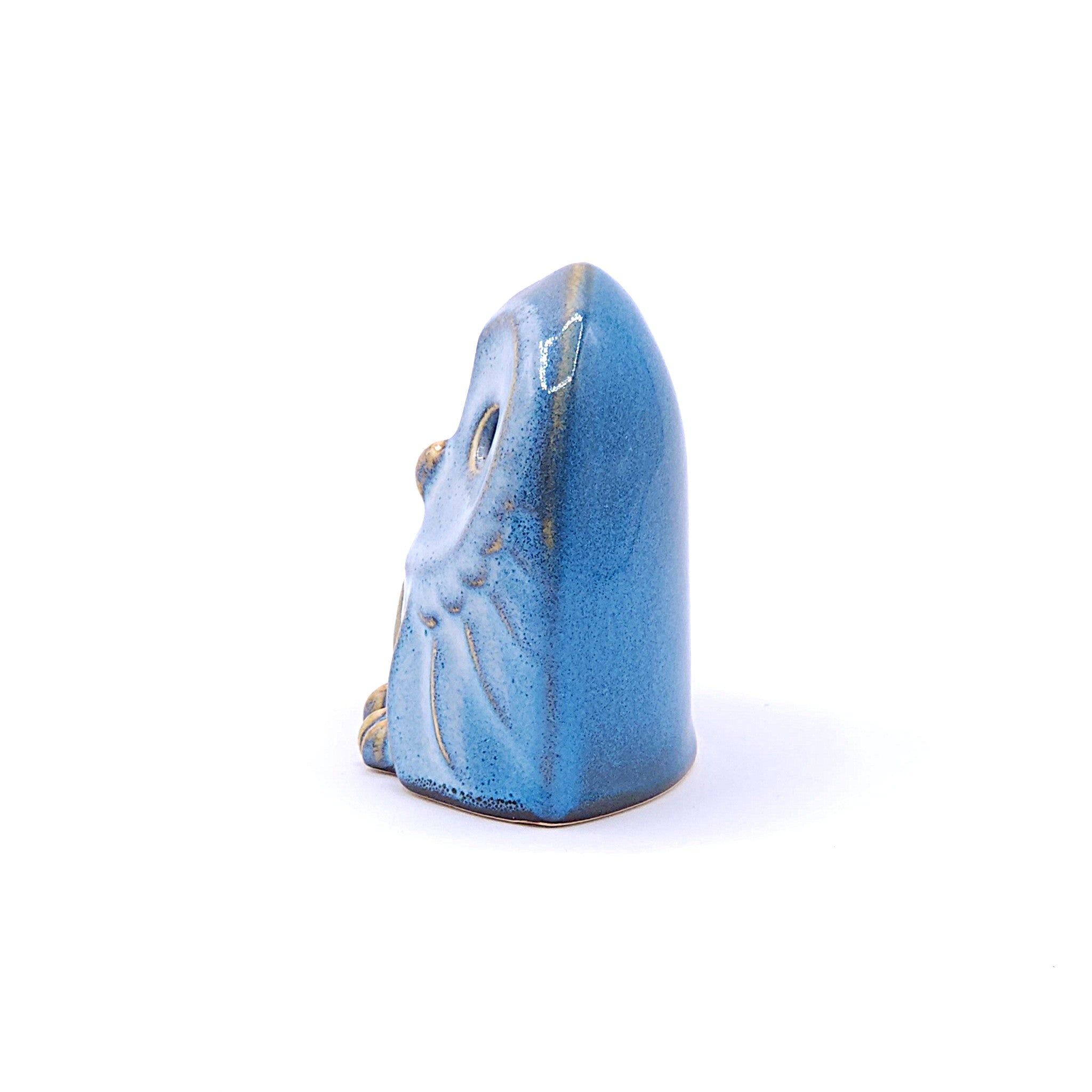 A left side view of a handcrafted ceramic figurine of an owl with a blue. Tsukushi