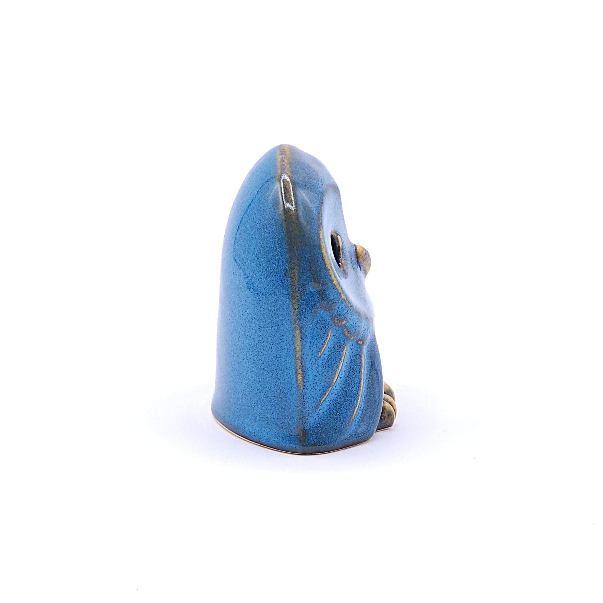 A right side view of a handcrafted ceramic figurine of an owl with a blue. Tsukushi