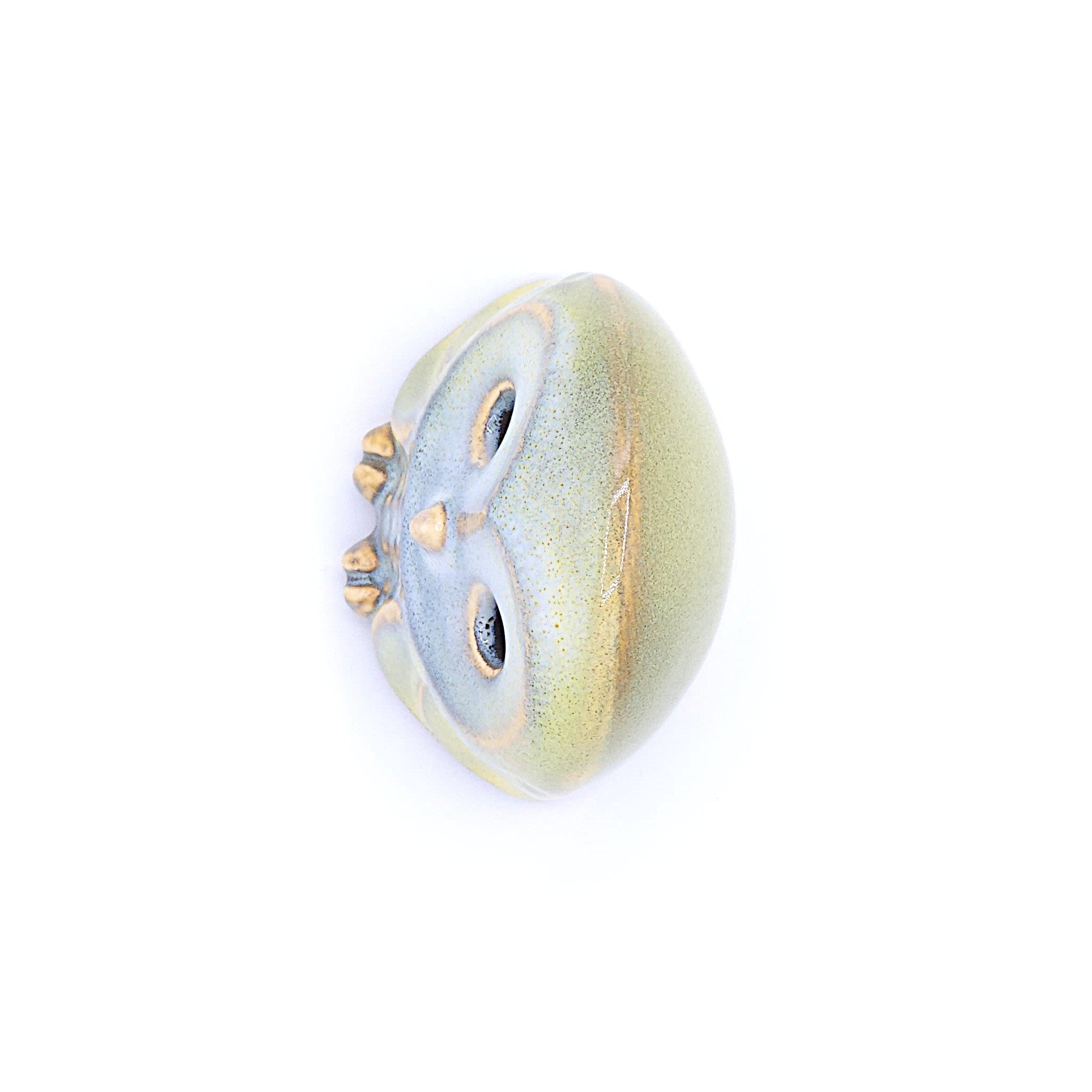 A top view of a handcrafted pottery figurine of an owl with a yellow. Tsukushi