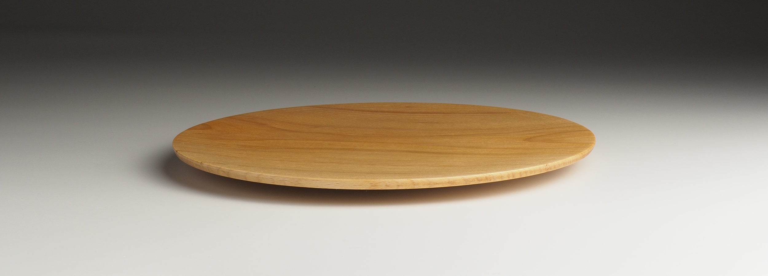 A Japanese wooden plate on a neutral background. Tsukushi