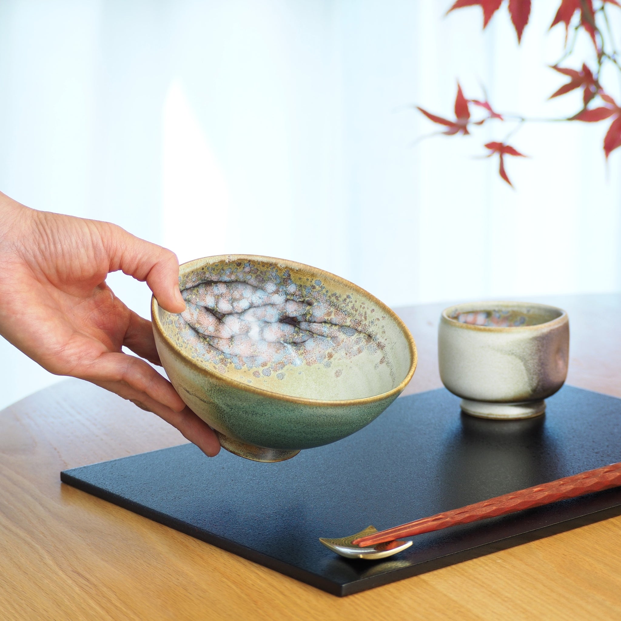 Japanese ceramic rice large bowl in green held by a woman hand. Tsukushi