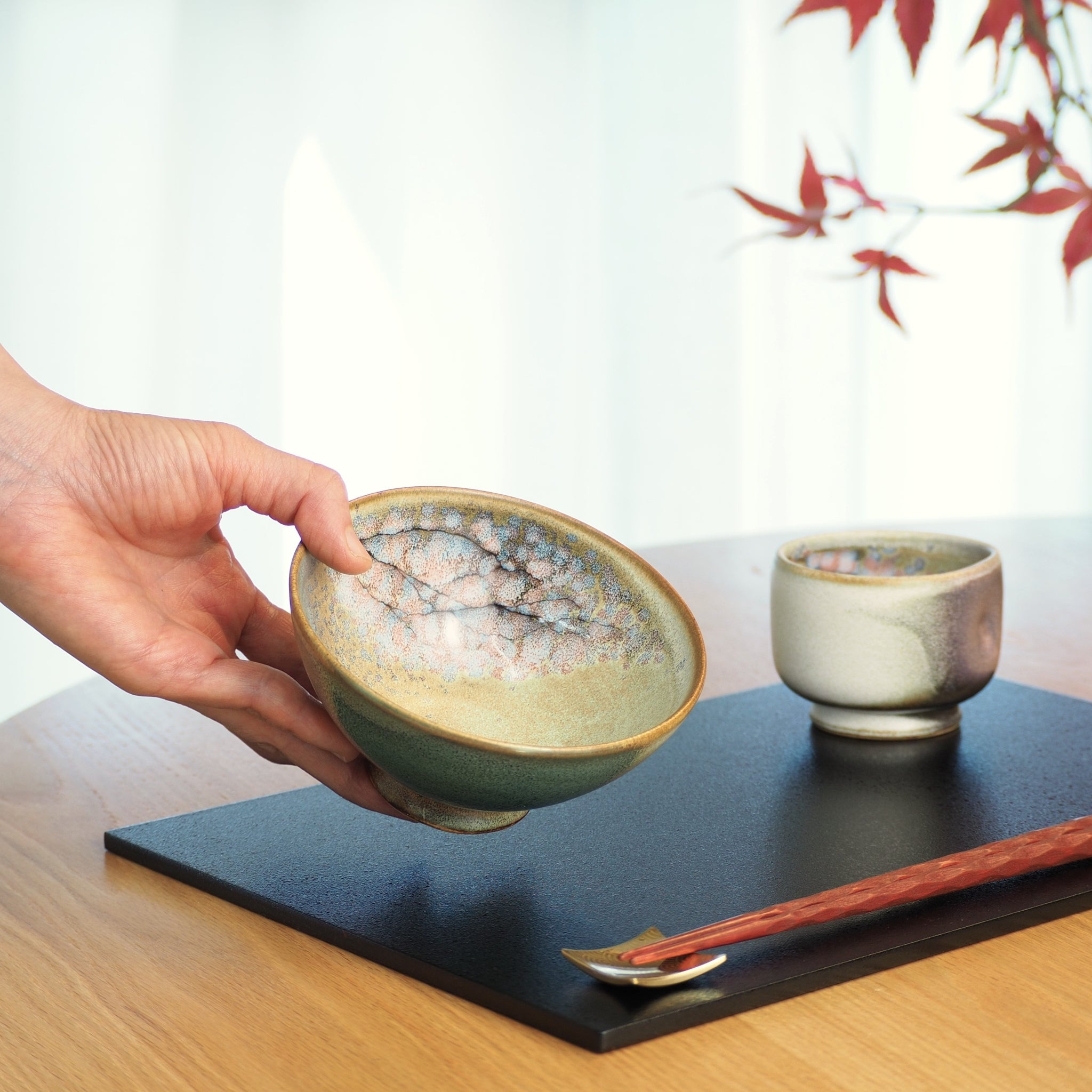 Japanese ceramic rice small bowl in green held by a woman hand. Tsukushi