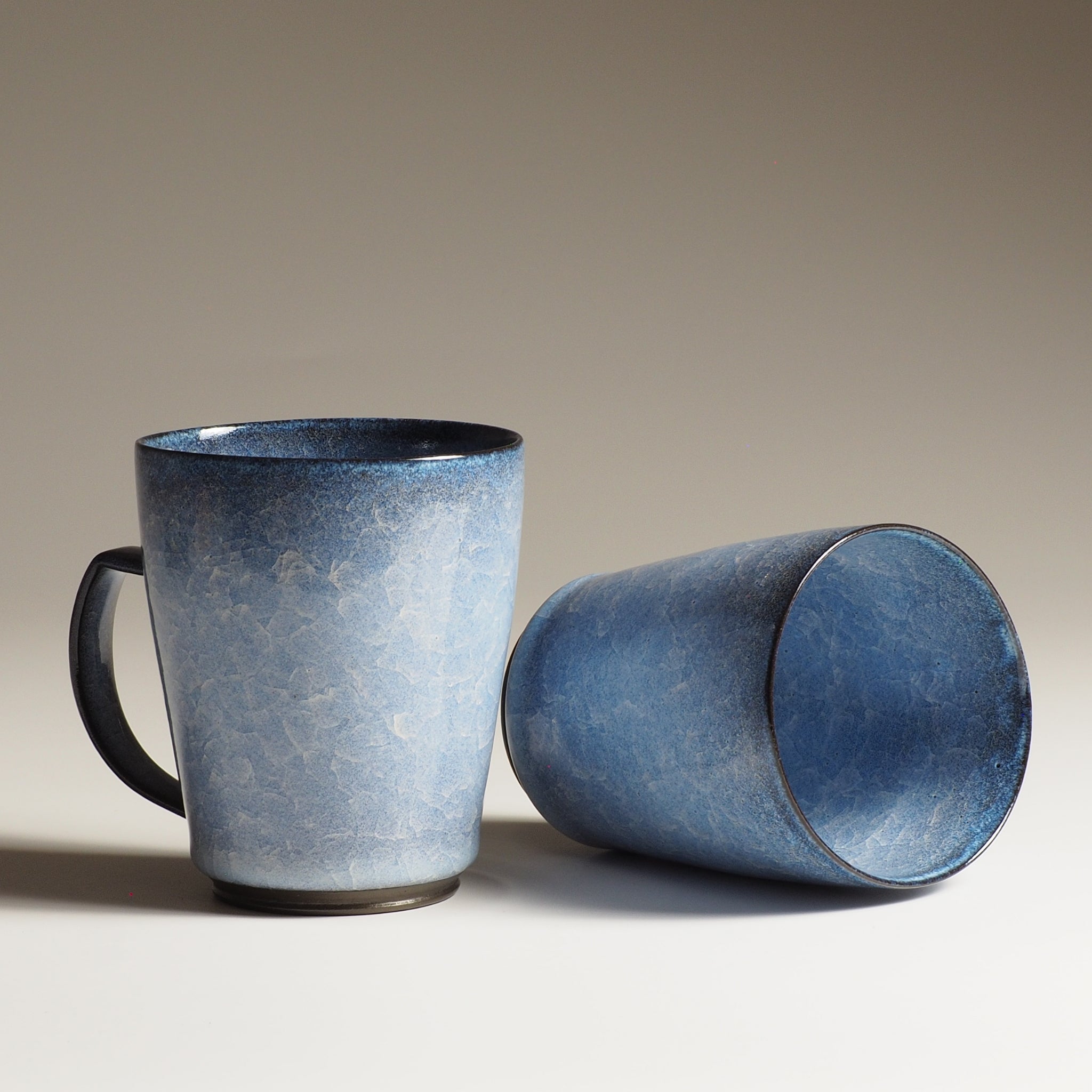 Japanese handcrafted crazing ceramic Tea mugs beige background one from side the other inside, Tsukushi