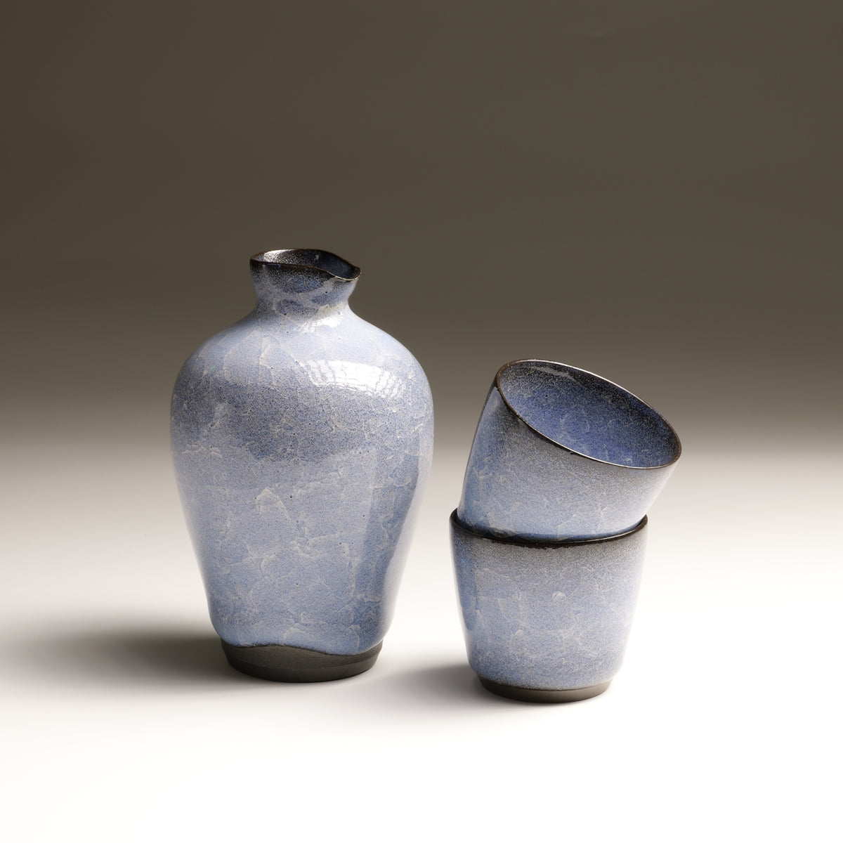 Seigen Japanese sake set with blue crackle-glazed tokkuri and two stacked ochoko cups