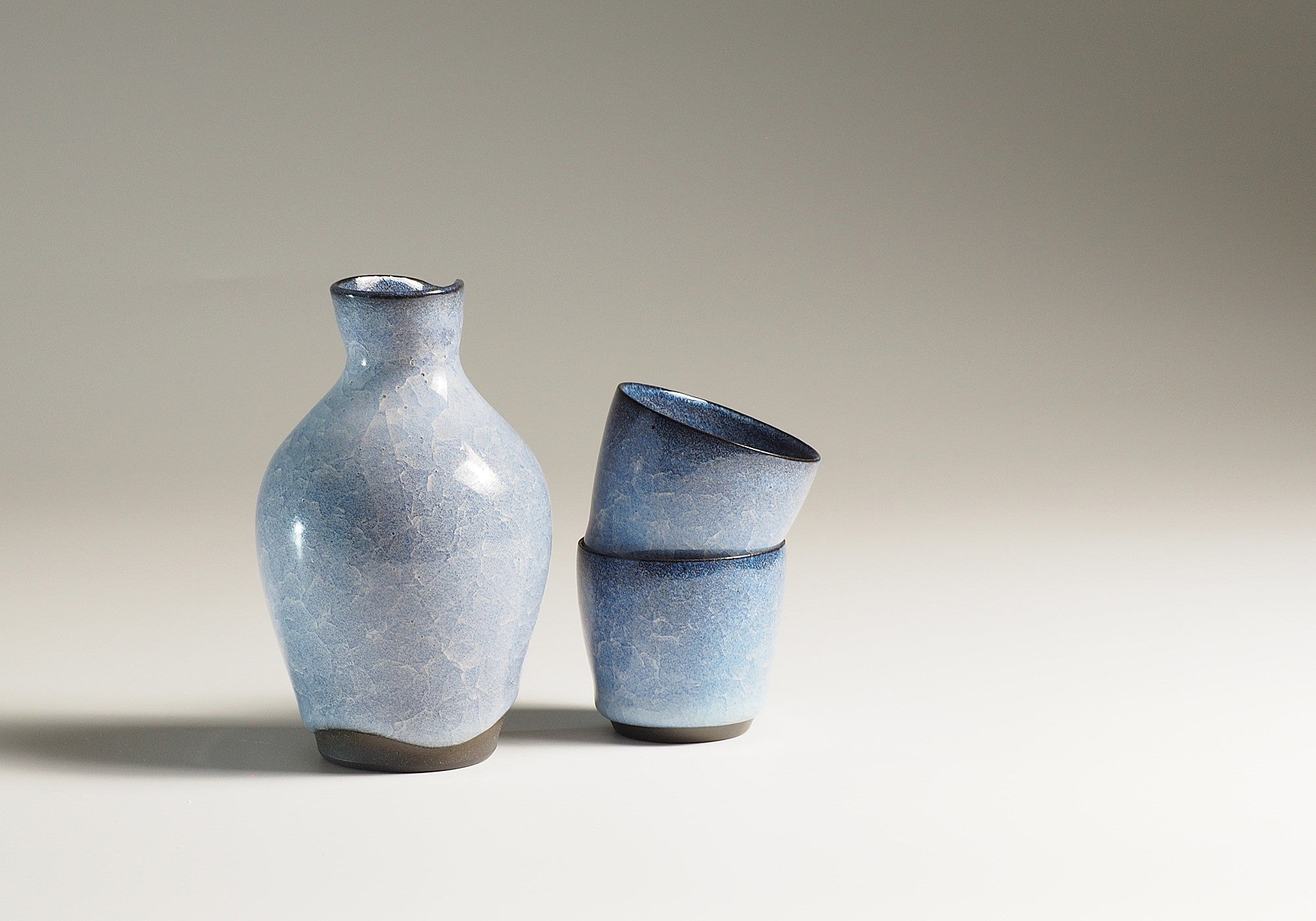 Handmade Japanese pottery crazed design Tokkuri and Sake cups beige background, Tsukushi