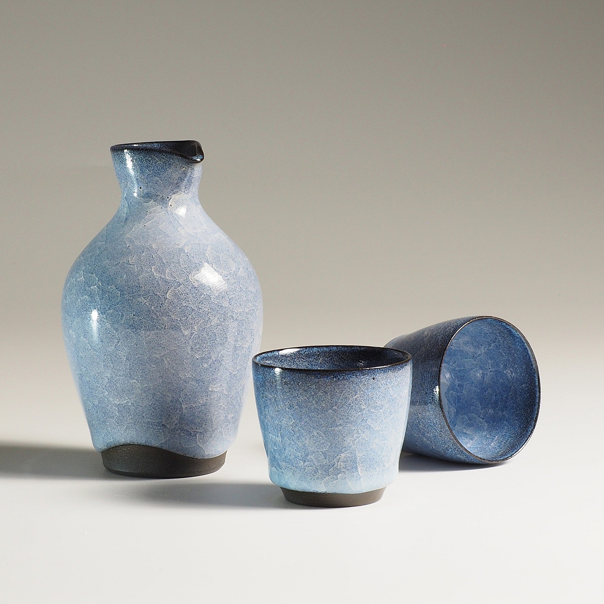 Japanese handcrafted crazing ceramic Sake set beige background with shadows, Tsukushi