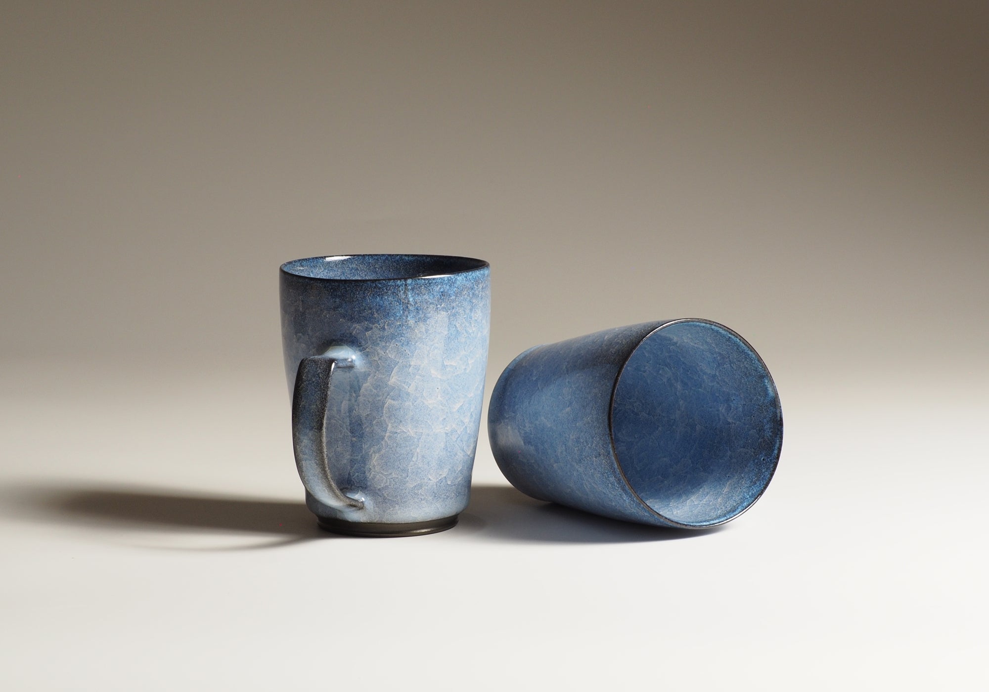 Japanese handcrafted crazing ceramic Tea mugs beige background with shadow one from side the other inside, Tsukushi