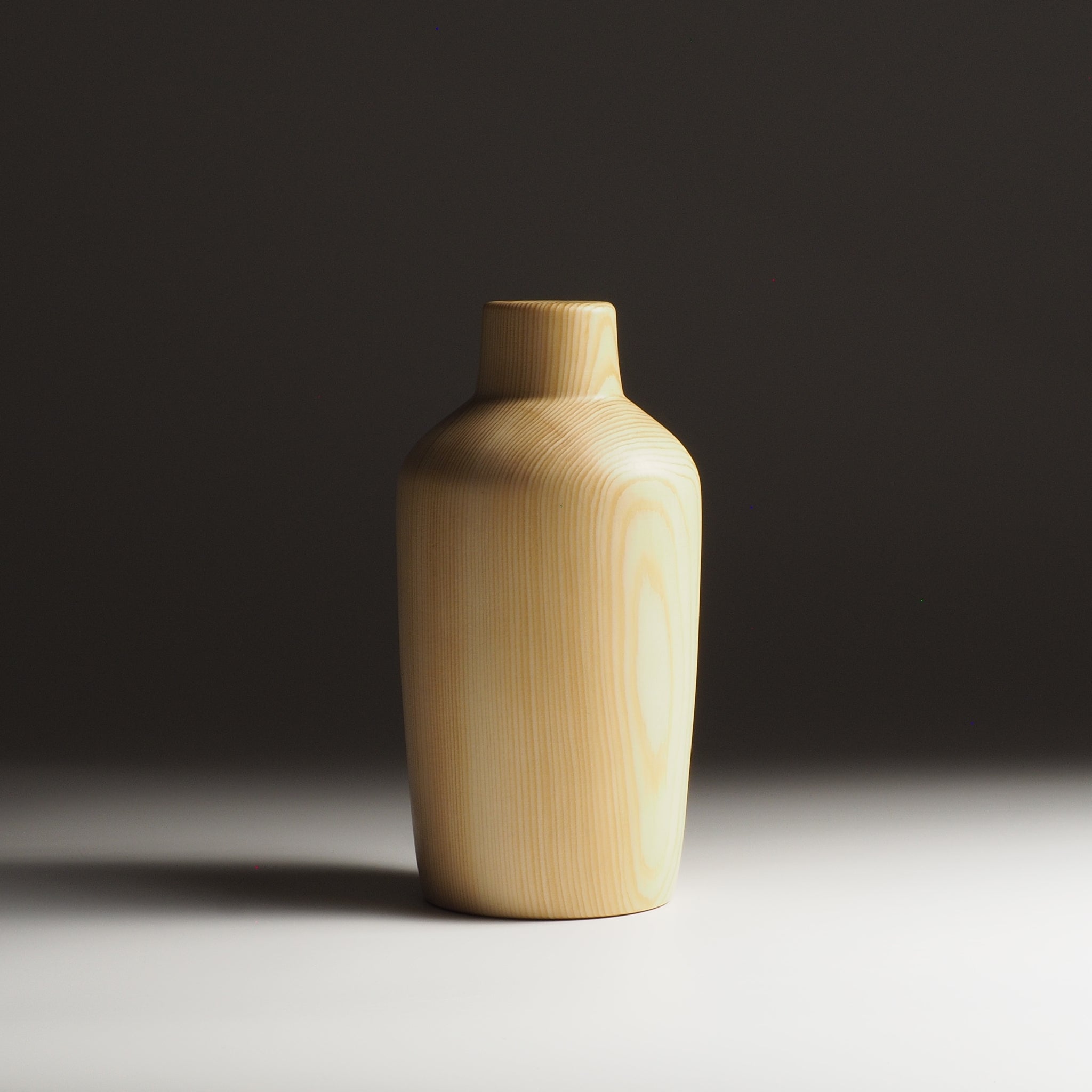 A Japanese wooden vase on dark beige gradient background. Tsukushi
