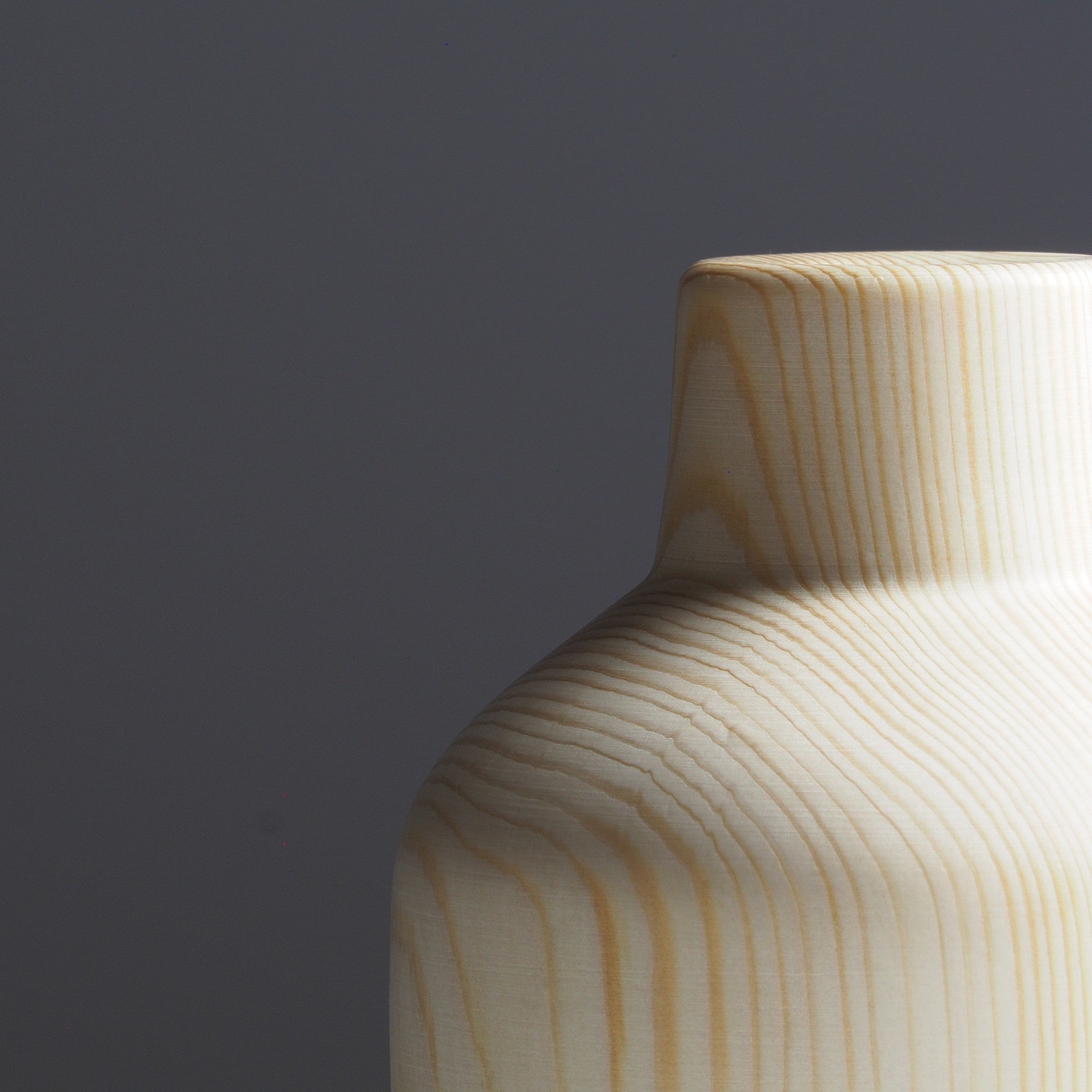 A close-up of a Japanese wooden vase on a light gray background. Tsukushi