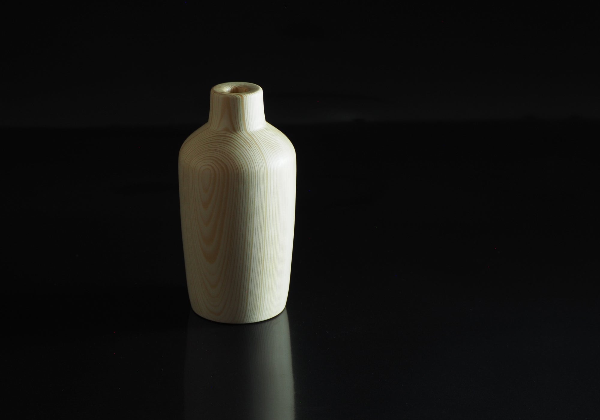 Japanese wooden vase on a black reflective surface. Tsukushi