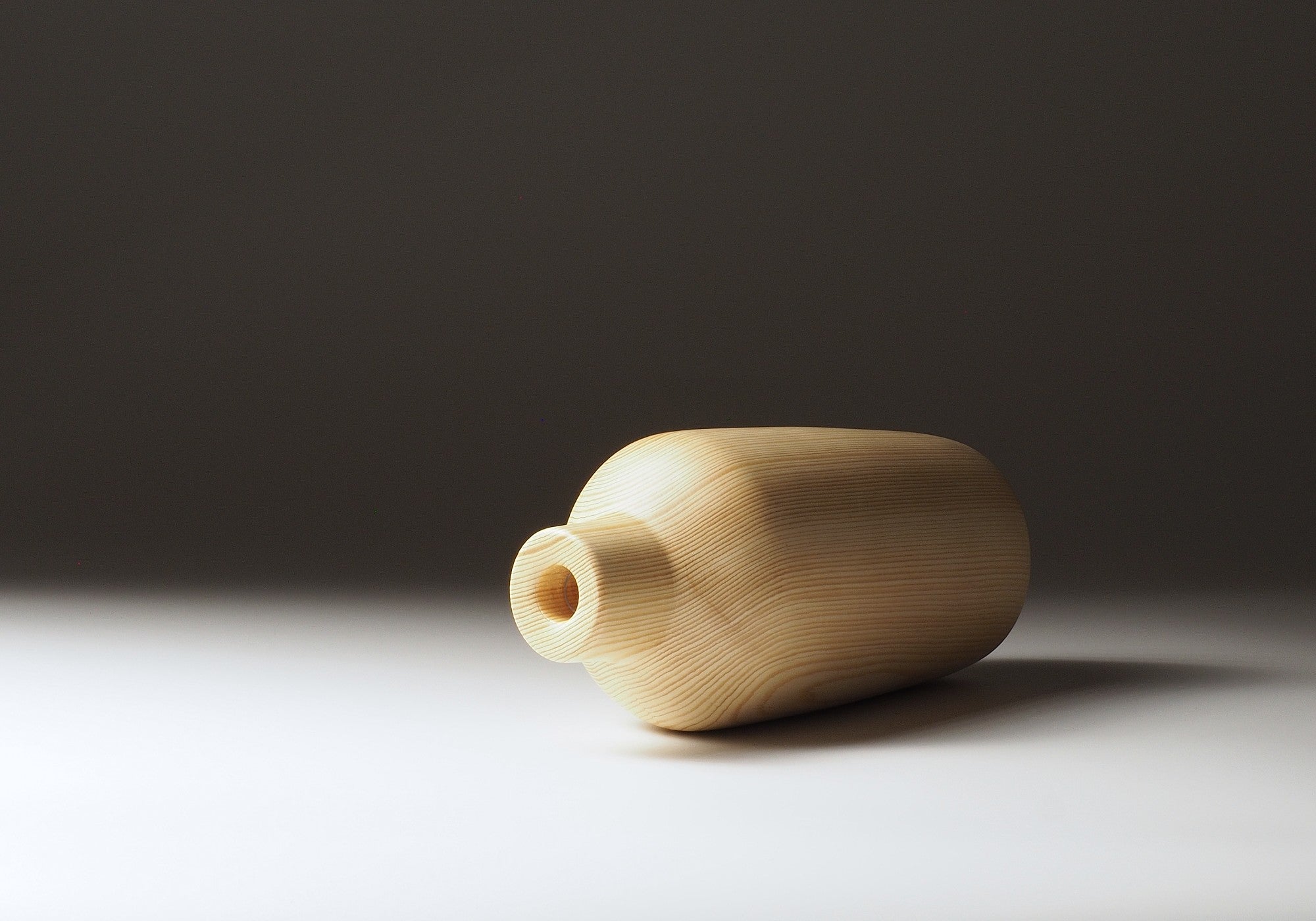 Japanese wooden vase called Shinon on a dark beige background. Tsukushi