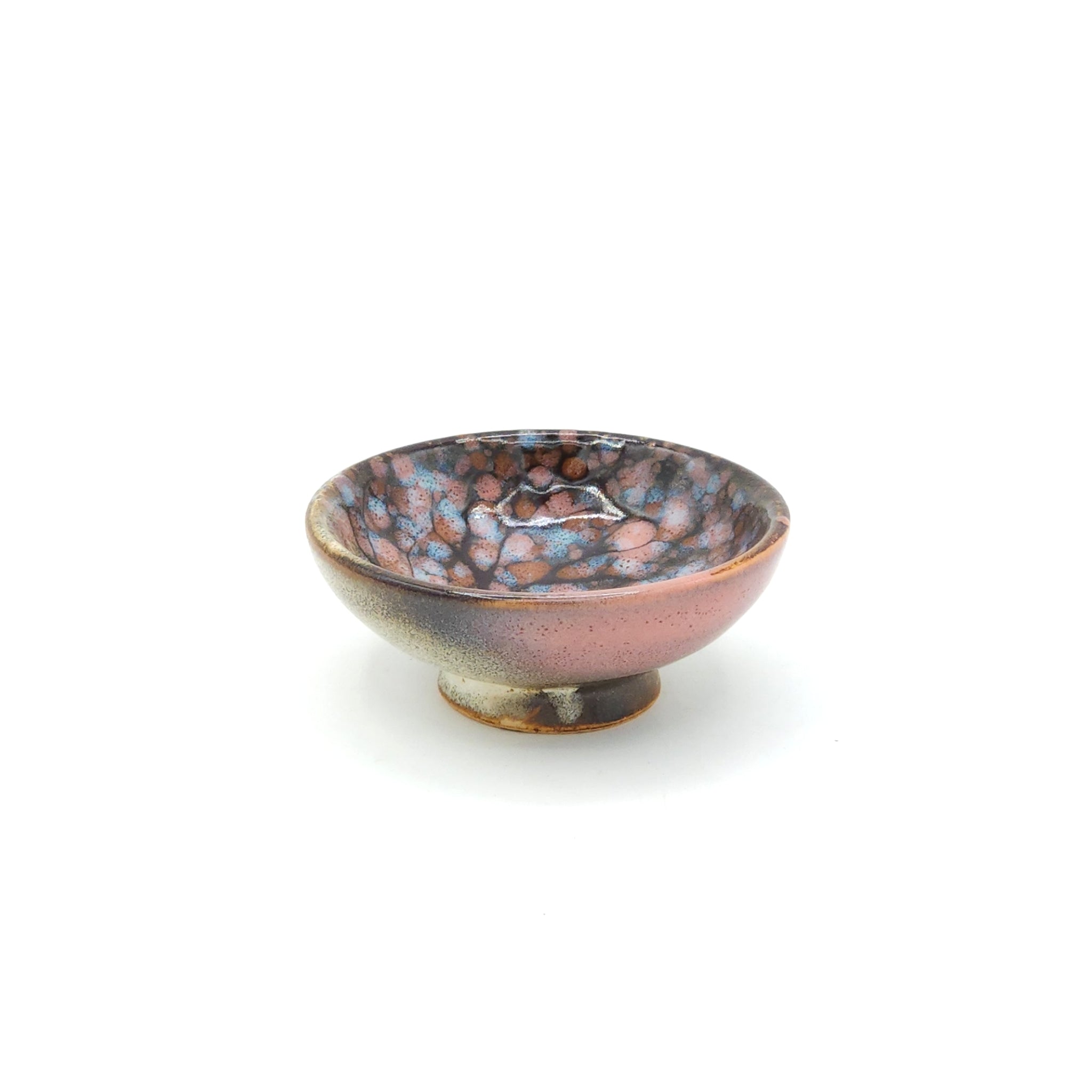 A side view of a flat Japanese ceramic sake cup with a cherry blossom motif. Tsukushi