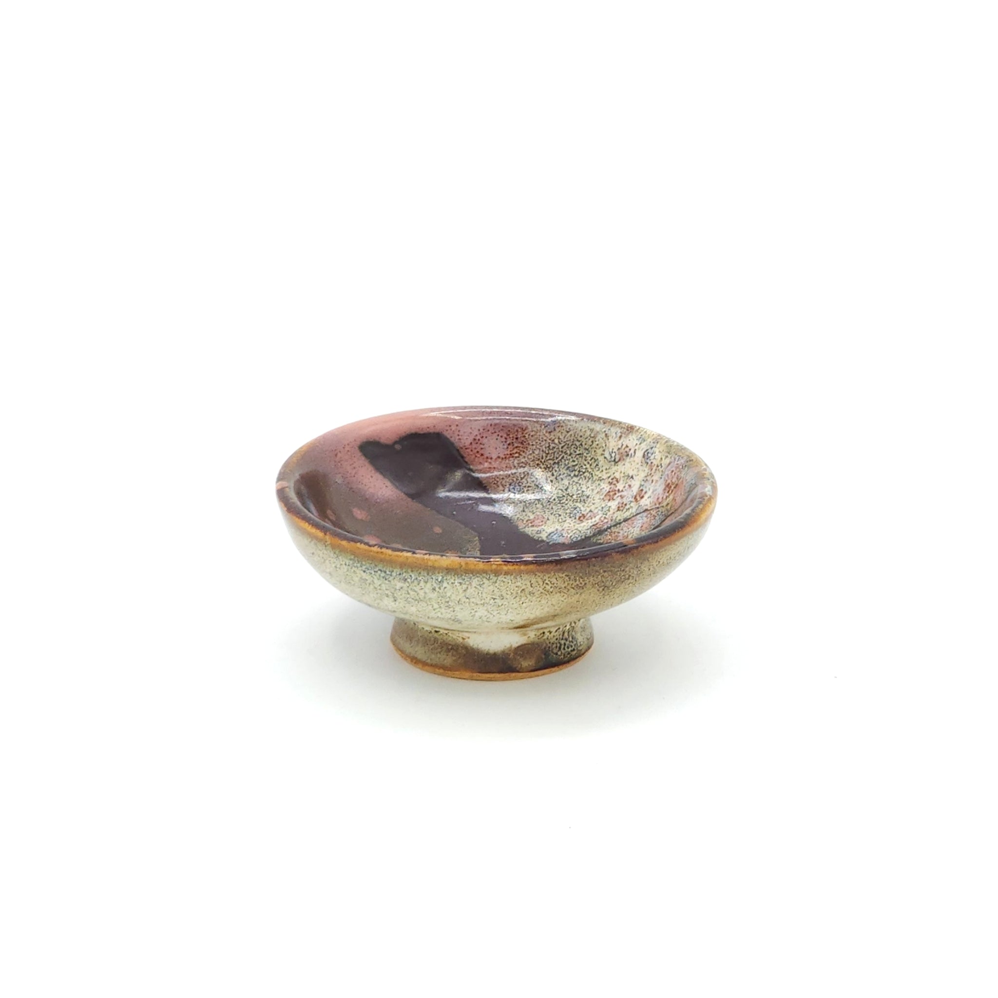 Frontal view of a flat Japanese ceramic sake cup with a cherry blossom motif. Tsukushi