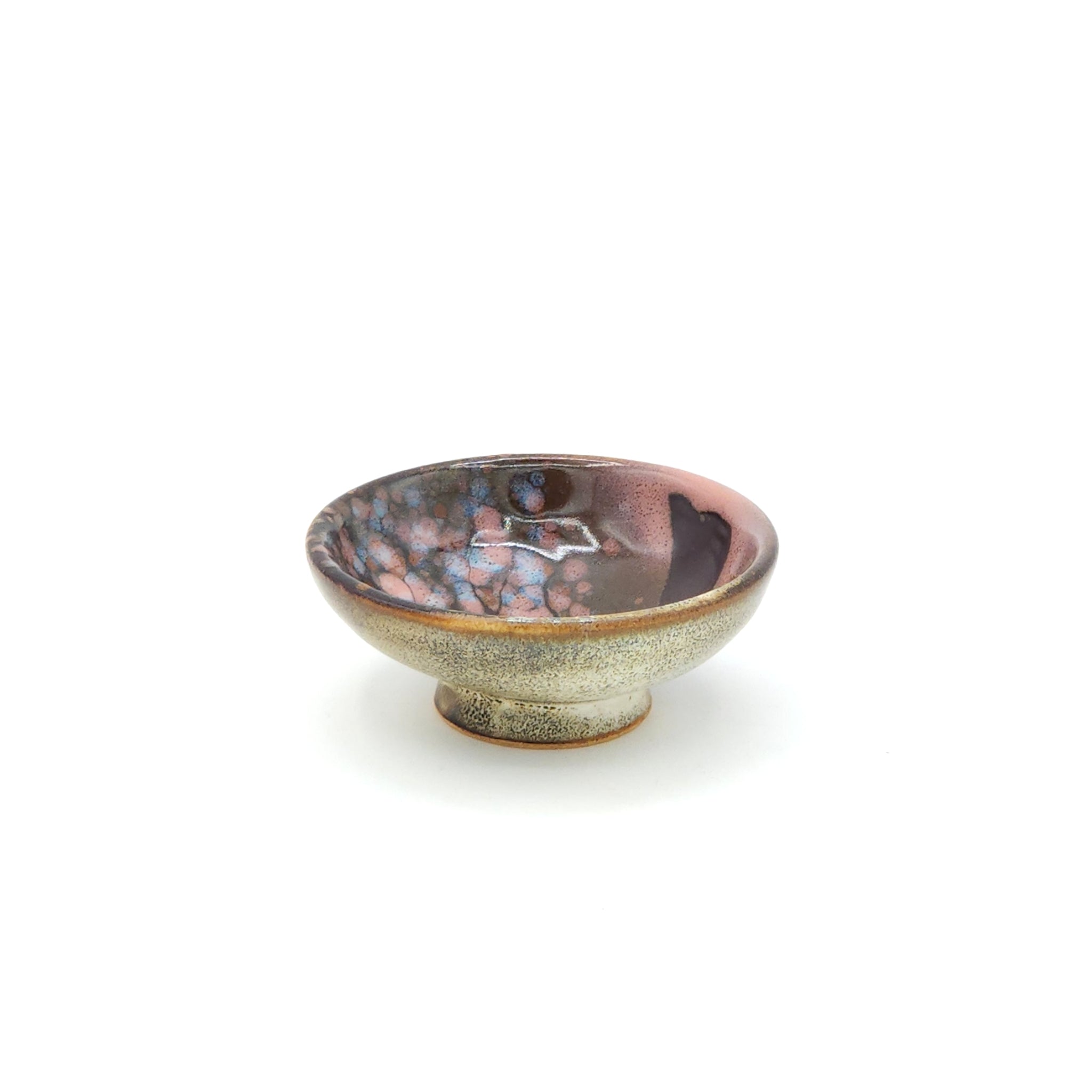 A side view of a flat Japanese ceramic sake cup with a cherry blossom motif. Tsukushi