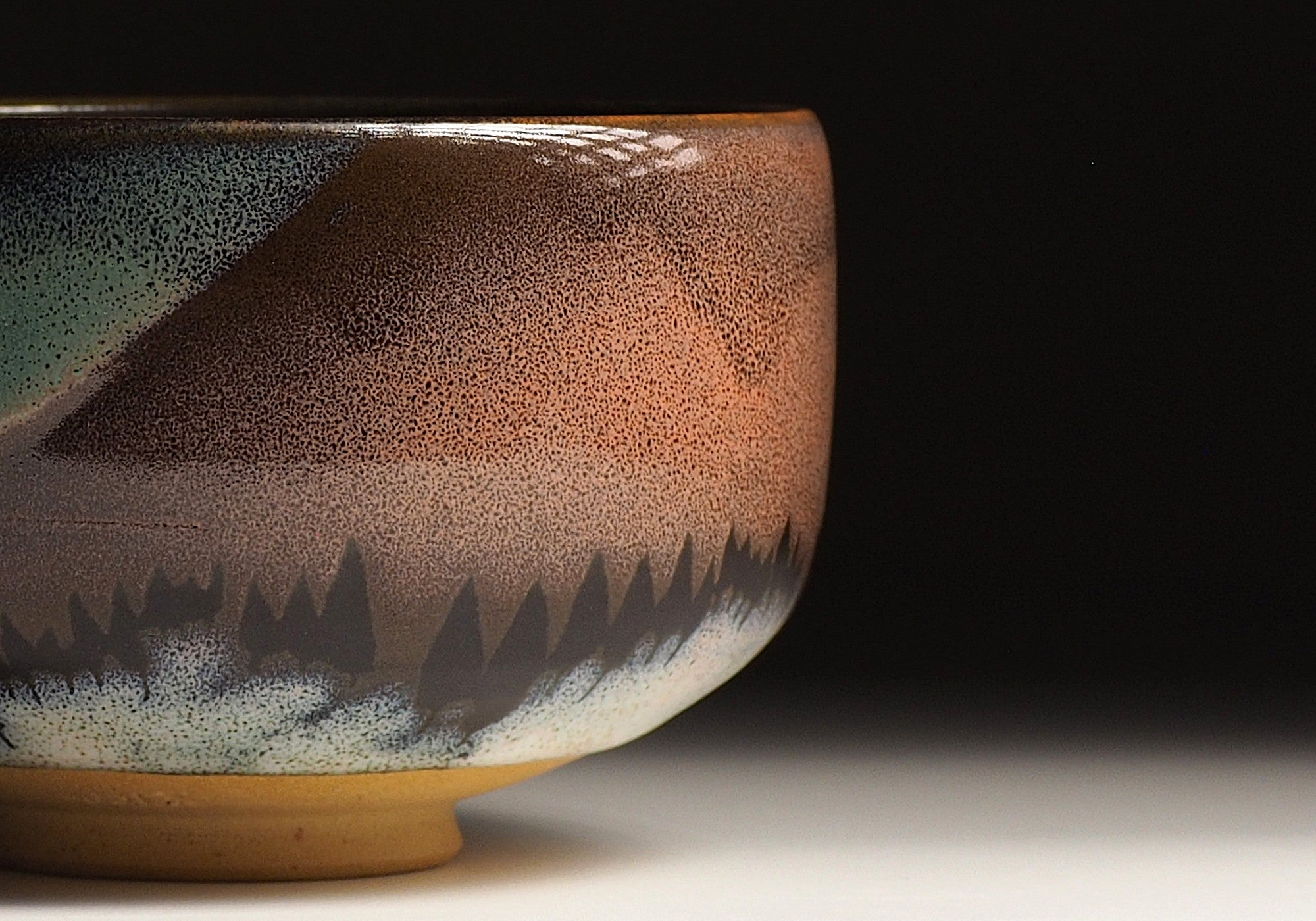 A close-up of a Japanese ceramic matcha bowl adorned with an Aurora against a black background. Tsukushi