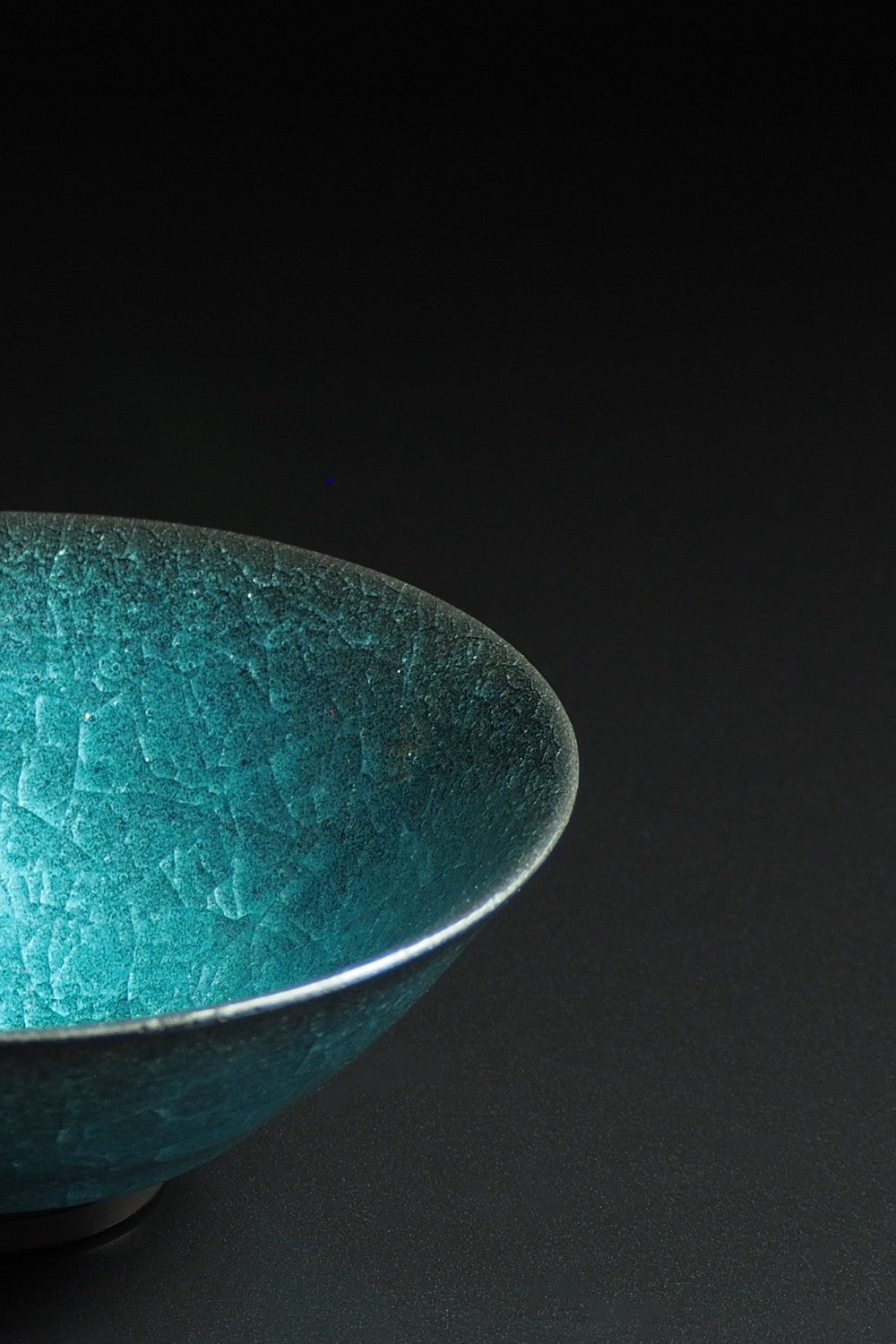 detail of a handcrafted crazing Japanese ceramic Donburi bowl on a black background , Tsukushi