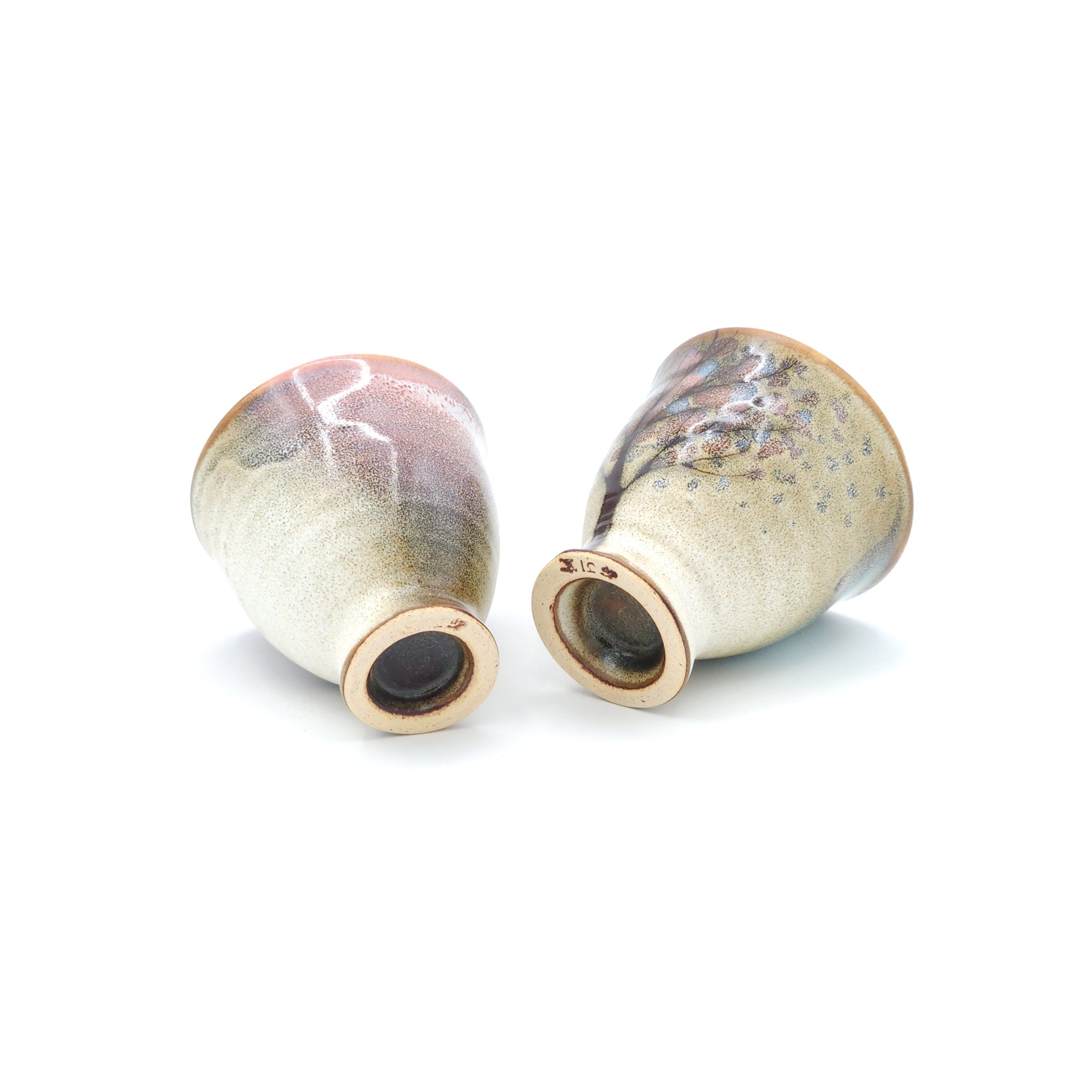 A bottom view of two Japanese ceramic Conical Sake cups with a cherry blossom pattern. Tsukushi