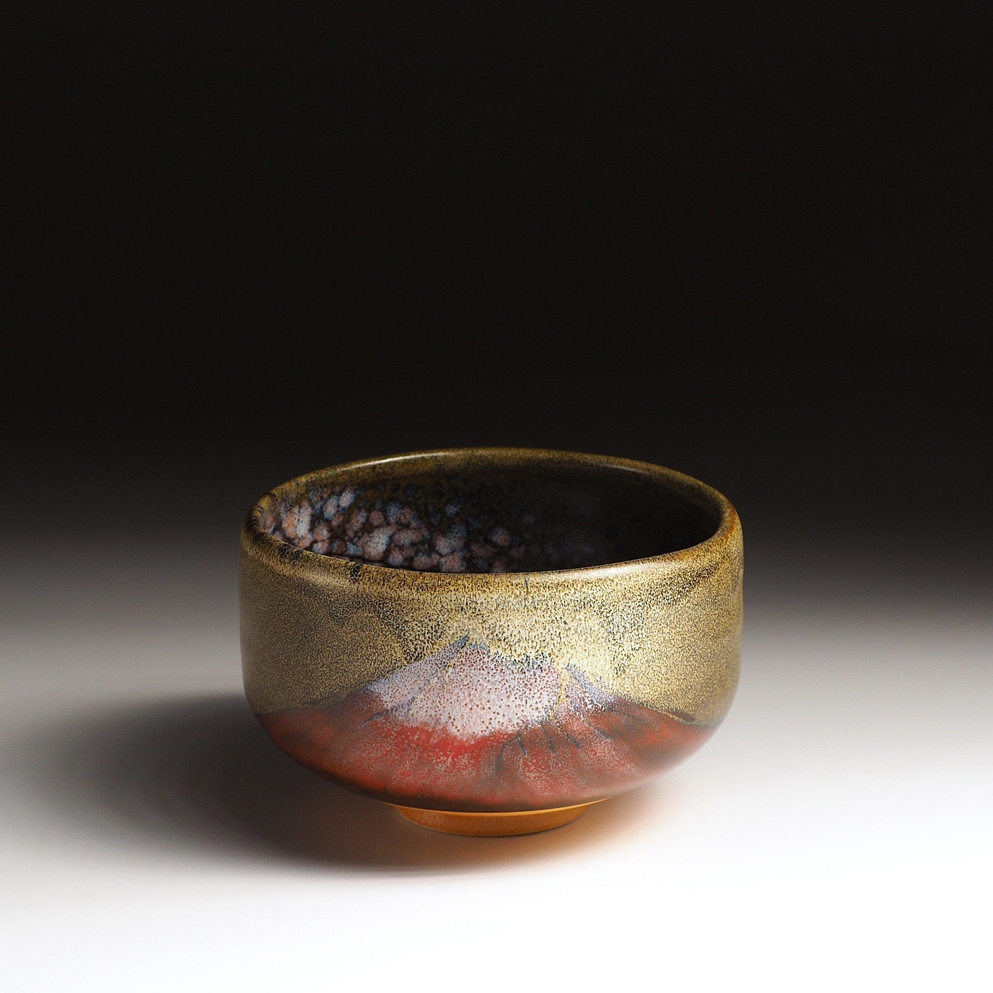 A Japanese ceramic matcha bowl depicting Mt.Fuji set against a dark background, Tsukushi