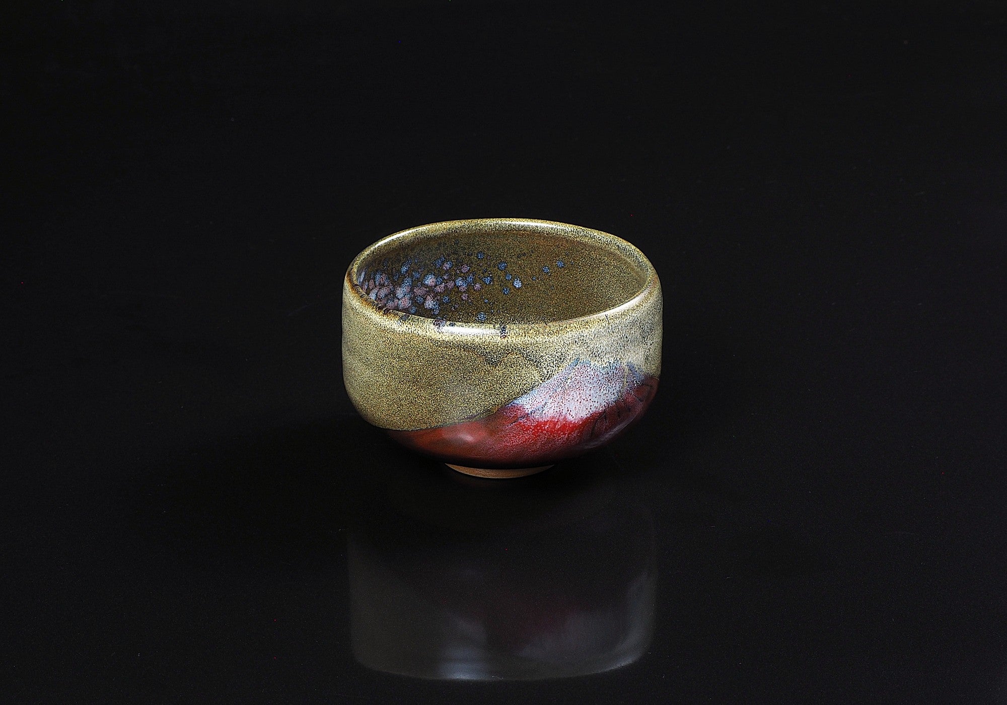 A Japanese ceramic matcha bowl designed with Mt. Red Fuji against a black background. Tsukushi