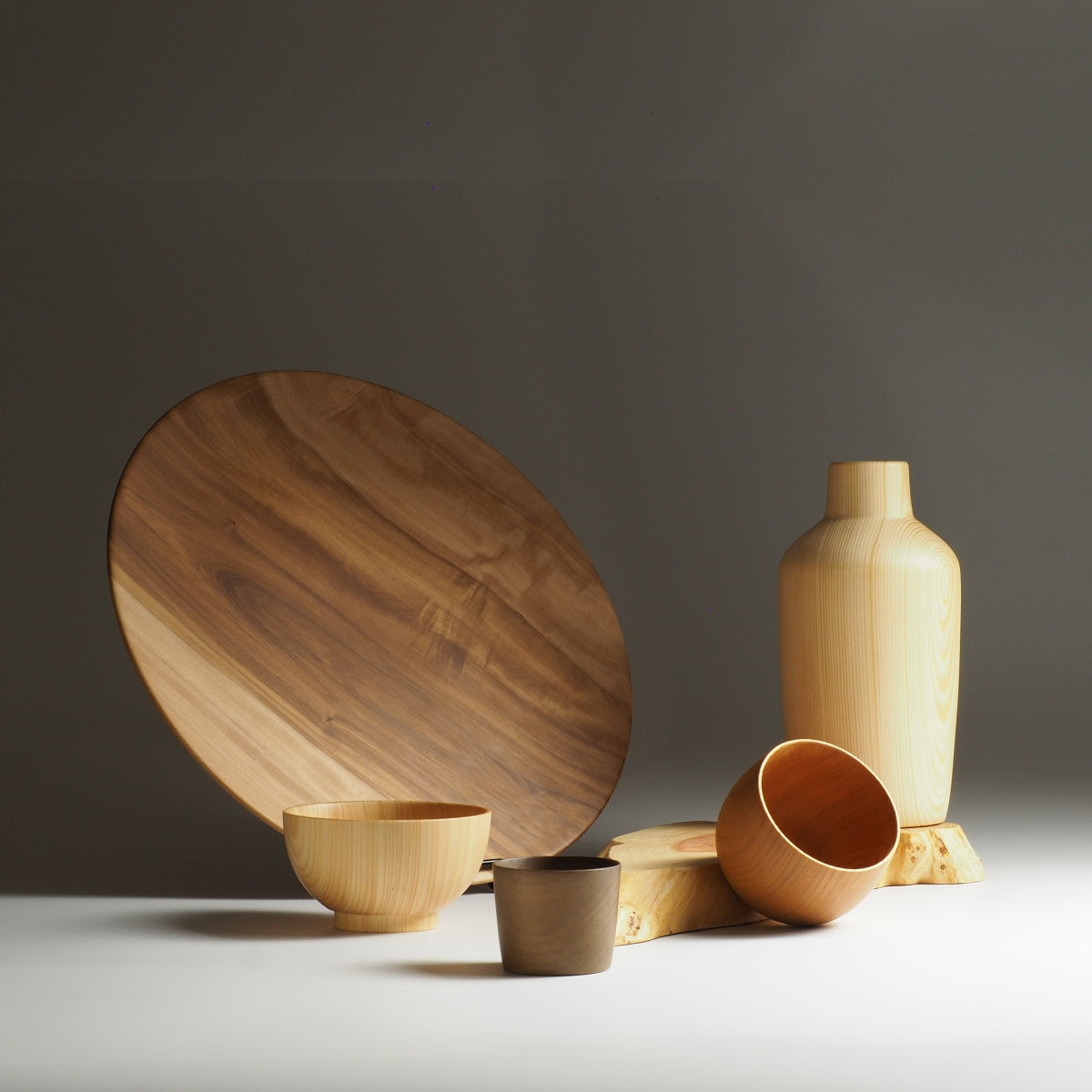 Set of Japanese wooden kitchenware a sushi tray, bowls, and a vase on a neutral background. Tsukushi
