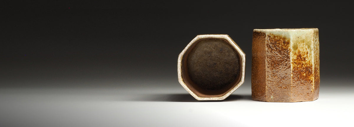 Two Hachiryō handmade Shigaraki octagonal cups, one upright and one facing forward to show the dark interior and faceted rim.