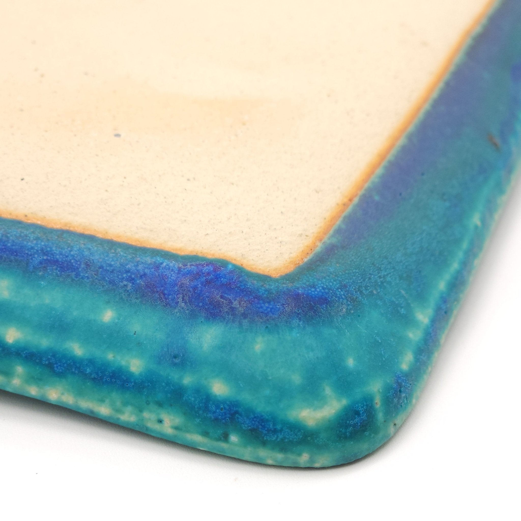 Bottom detail of an angle of a turquoise Japanese pottery plate measuring 21.5cm (8.5")