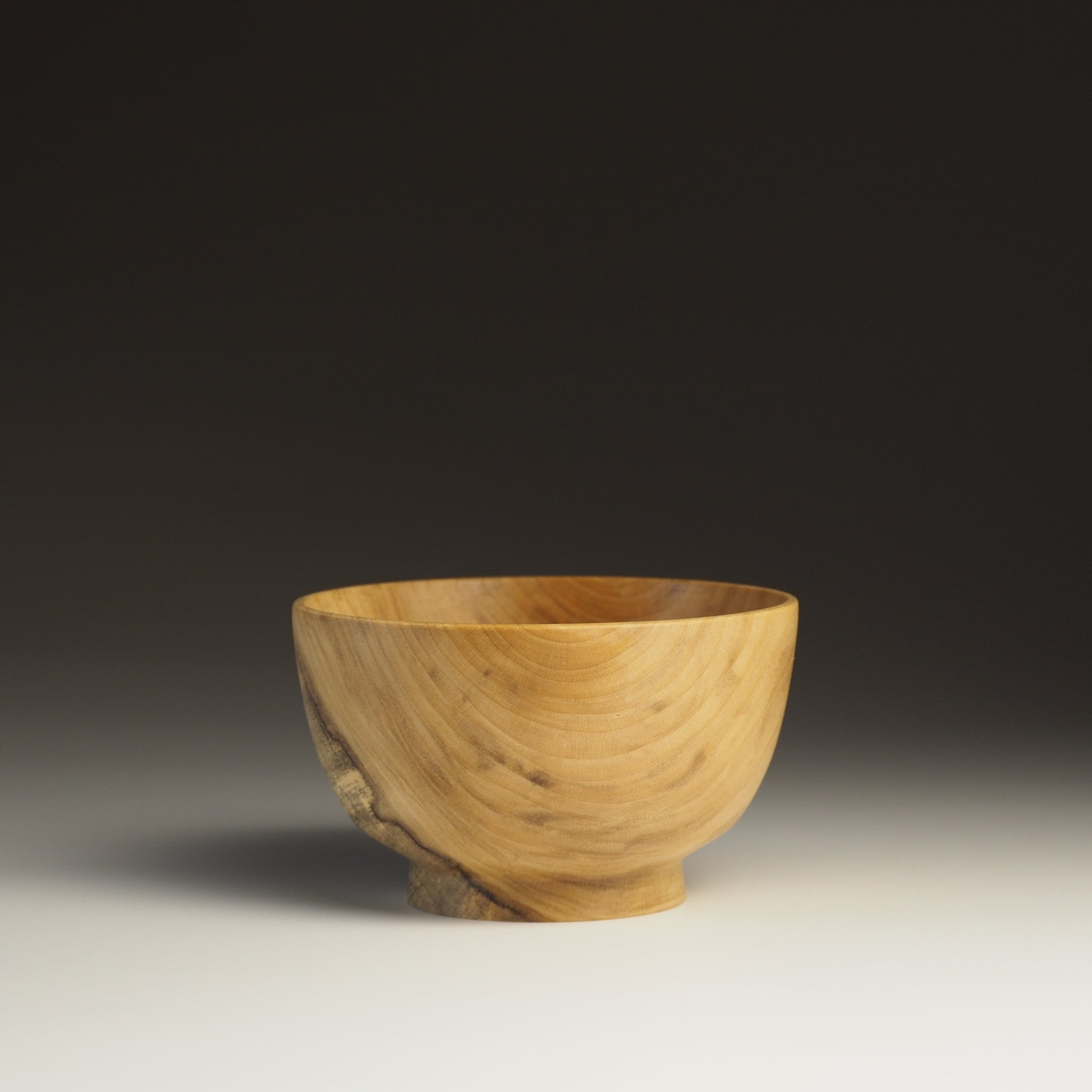 A front view of a Japanese Wooden Bowl on a beige gradient background. Tsukushi