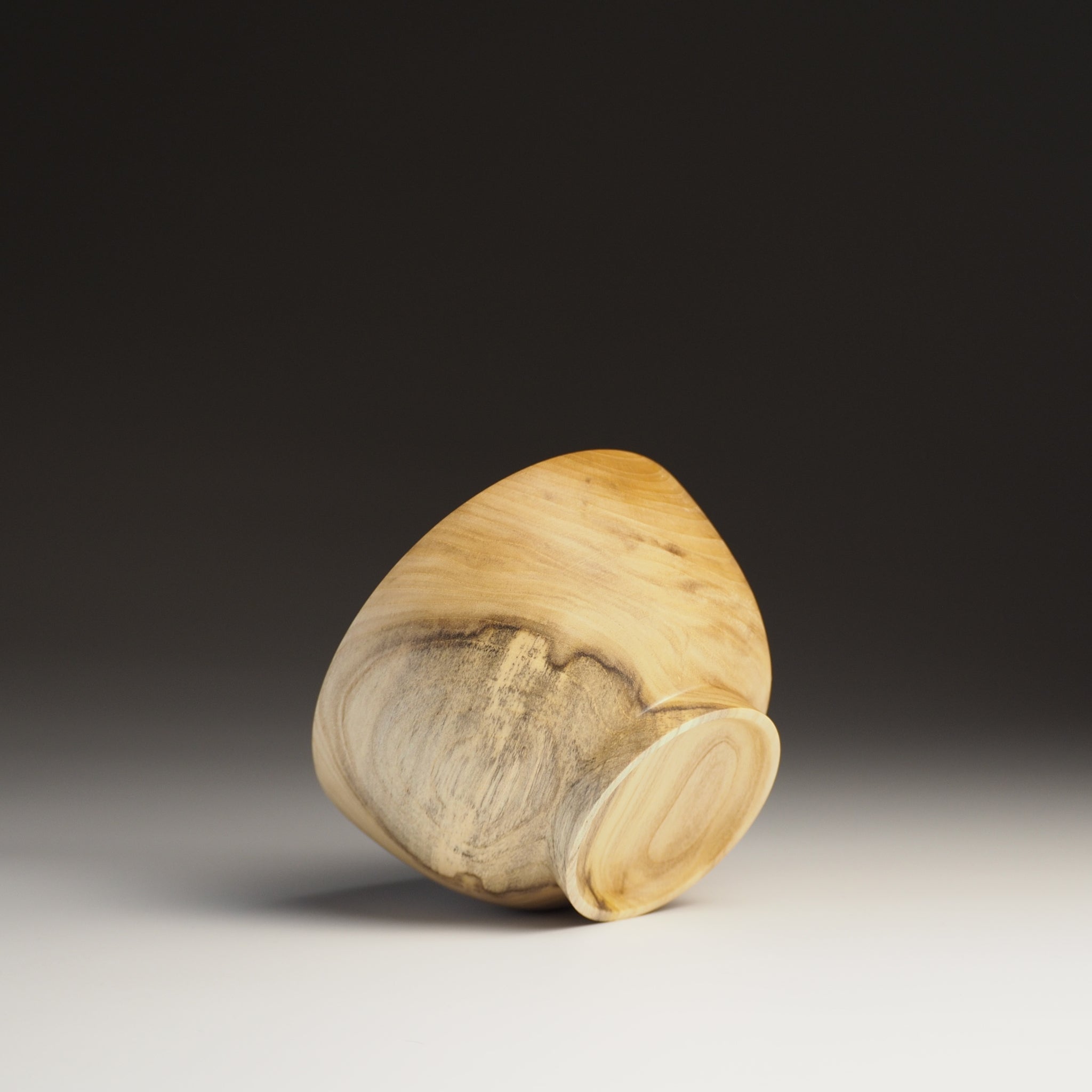 A bottom view of a Japanese Wooden Bowl on a black background. Tsukushi