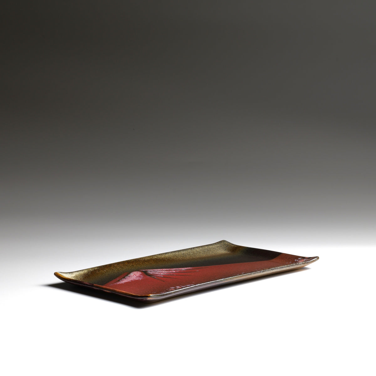Low-angle view of Akafuji Japanese pottery plate showing its shallow rectangular form