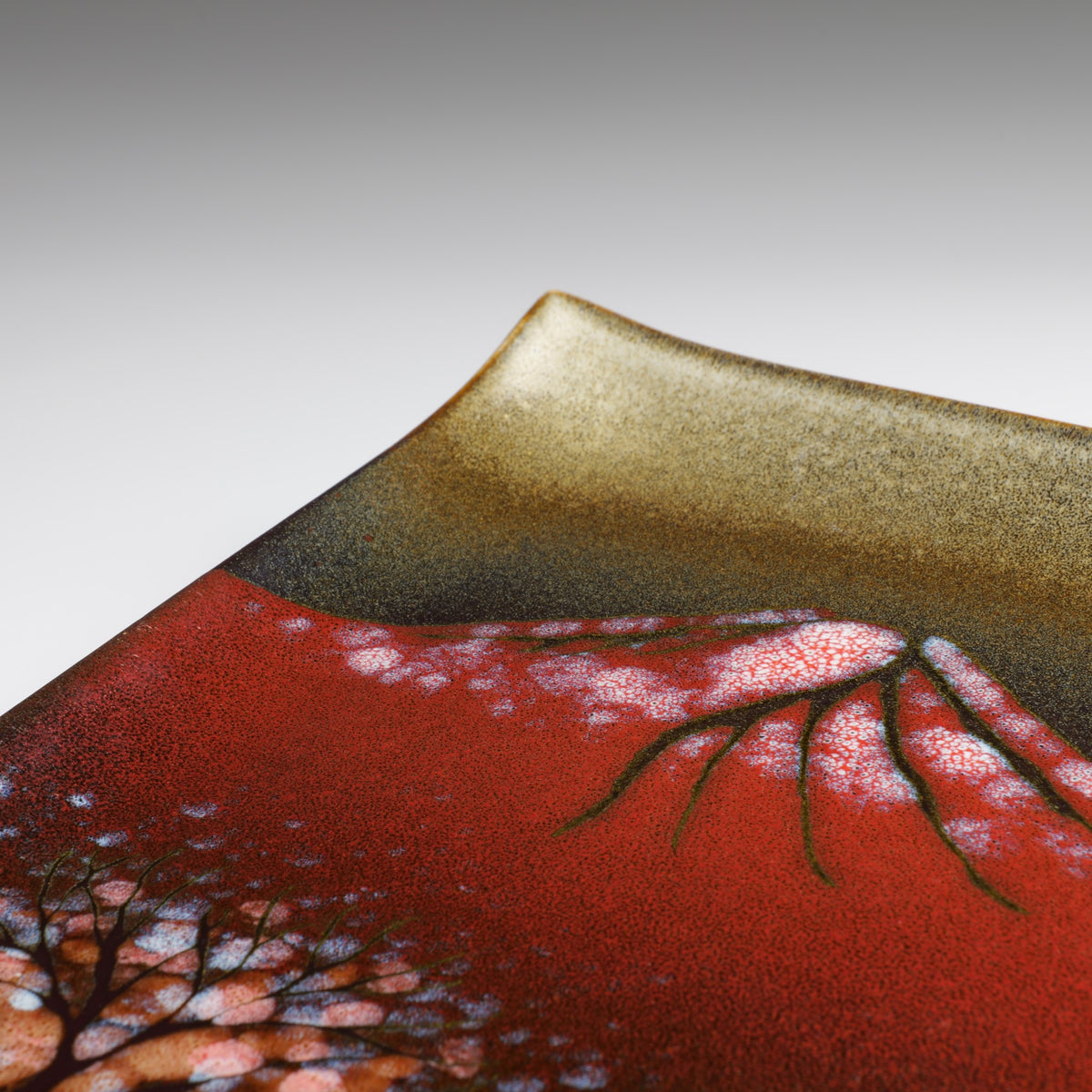 Detailed view of the Akafuji square ceramic plate featuring red Mount Fuji, white snow accents, dark branches, and textured glaze.