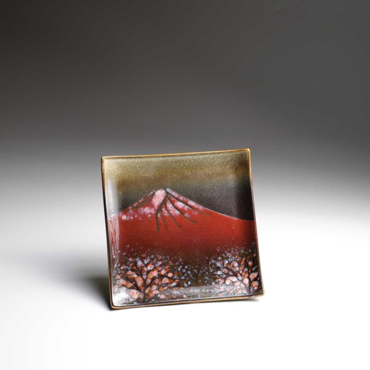 Handmade Akafuji square ceramic plate featuring red Mount Fuji, snow-covered peaks, and sakura trees against a dark glazed background.