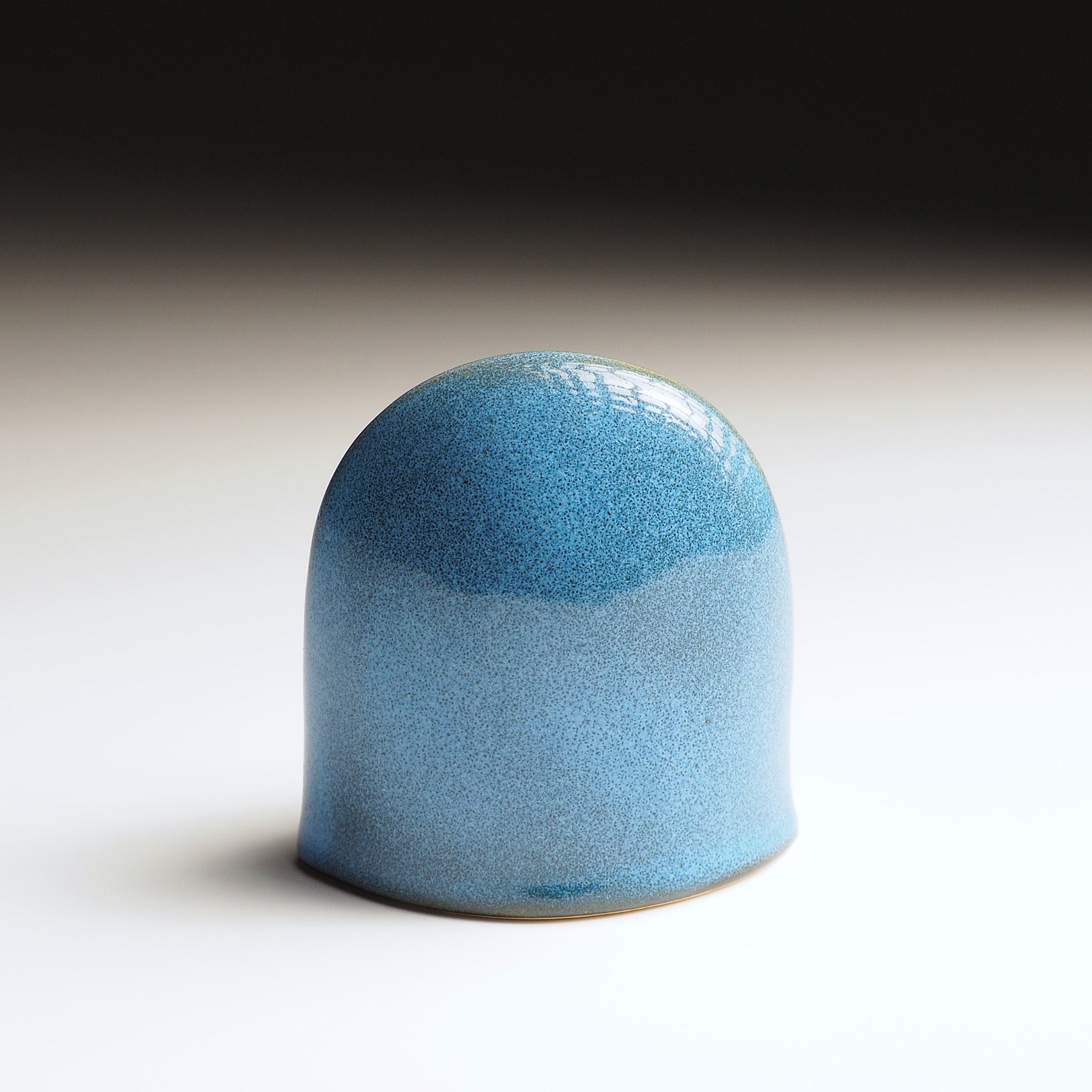 Rear view of Engifuku, ceramic owl figurine by Kazuhiro Kojima, blue speckled ceramic glaze, golden accents, dark eyes, gradient background.