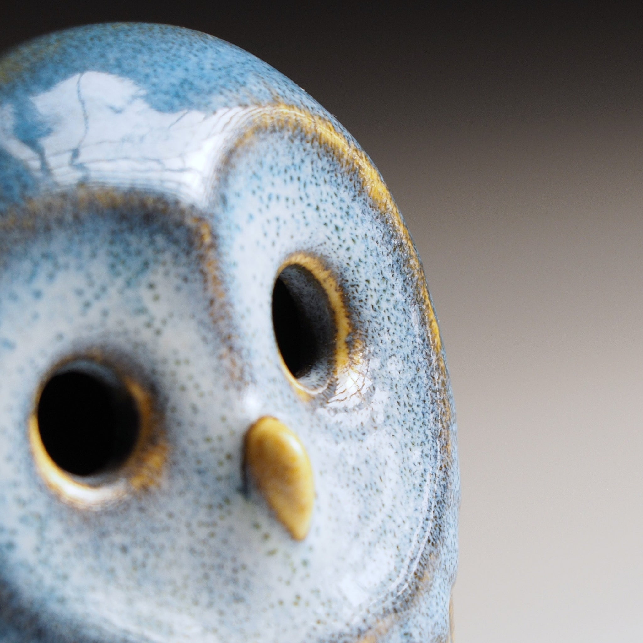 Close-up of Engifuku owl figurine by Kazuhiro Kojima, showing blue speckled glaze, golden-rimmed eyes and beak detail.