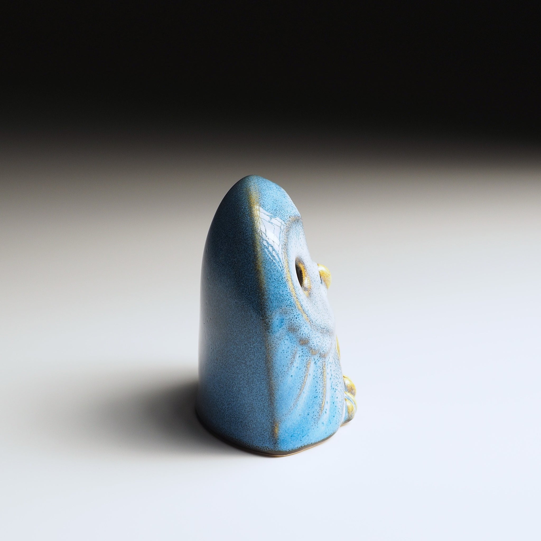 Right side view of Engifuku owl figurine by Kazuhiro Kojima, blue speckled ceramic glaze, golden accents, dark eyes, gradient background.