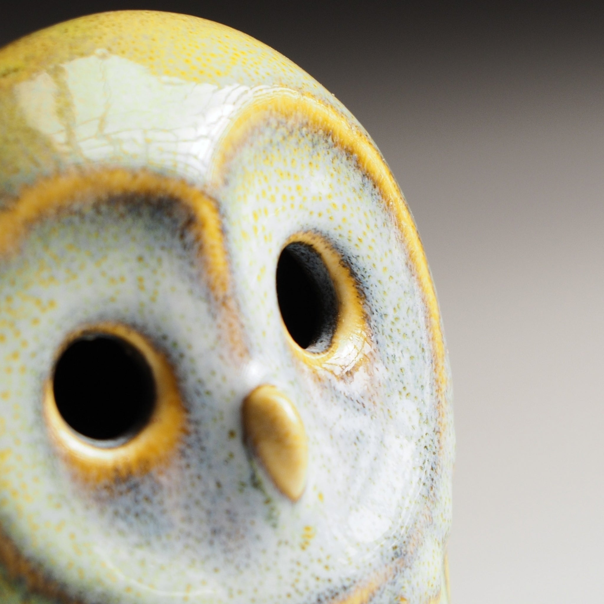 Close-up view of Engifuku owl figurine by Kazuhiro Kojima, blue speckled ceramic glaze, golden accents, hollow eyes, gradient background.
