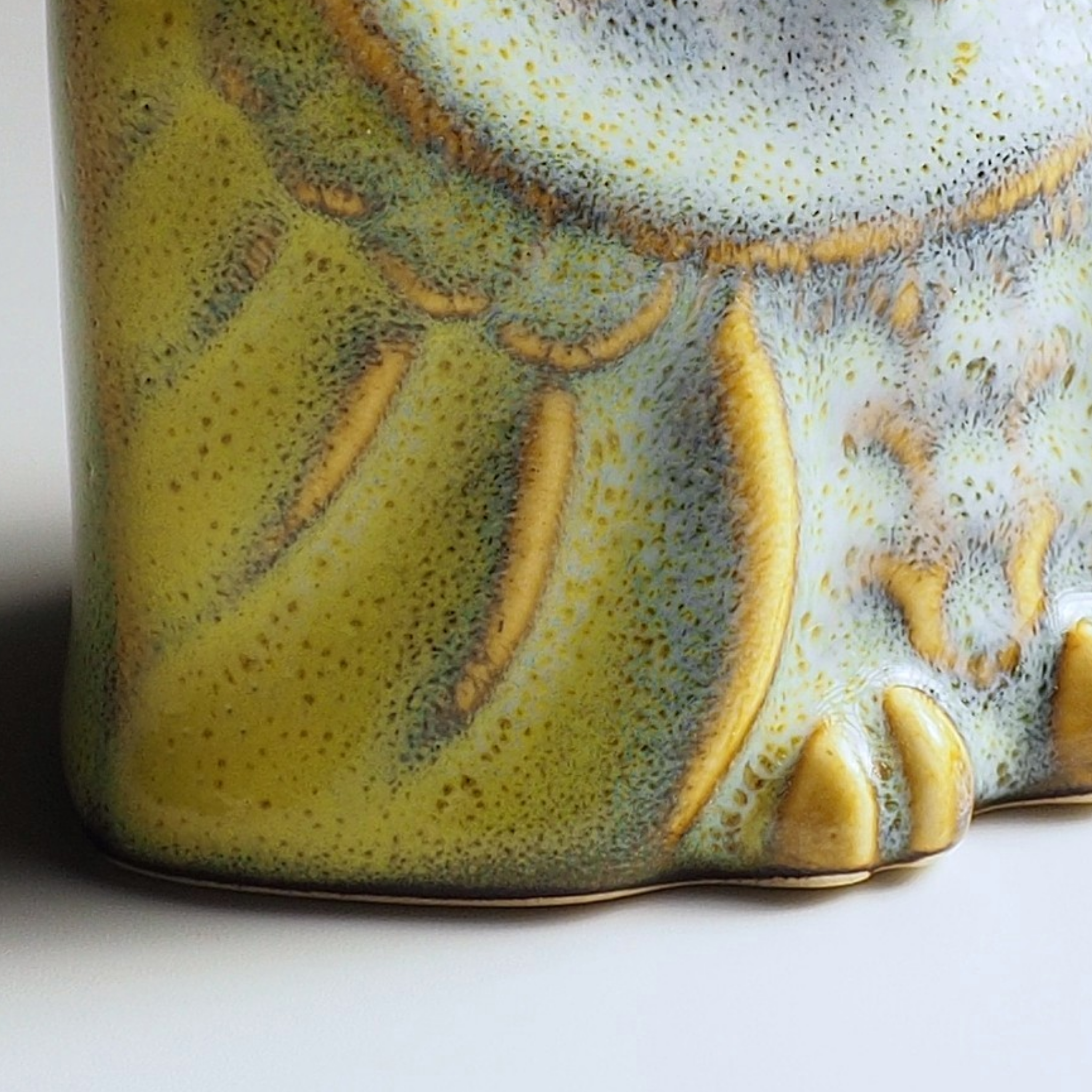 Close-up of the Engifuku ceramic owl with textured green and brown glaze on a white background