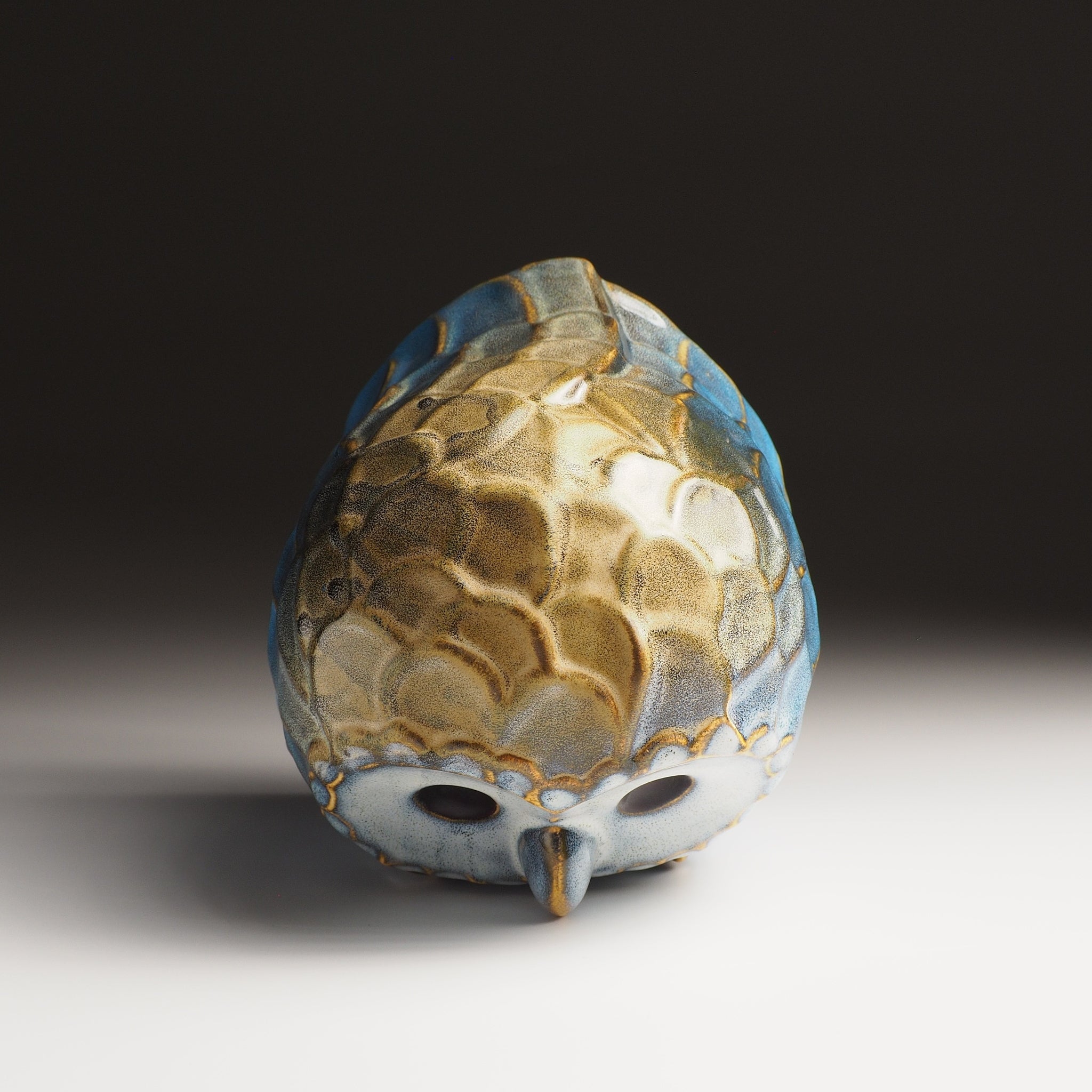 Top view of the large Fukumori ceramic owl figurine by Kazuhiro Kojima, amber and cerulean glaze on a faded background.