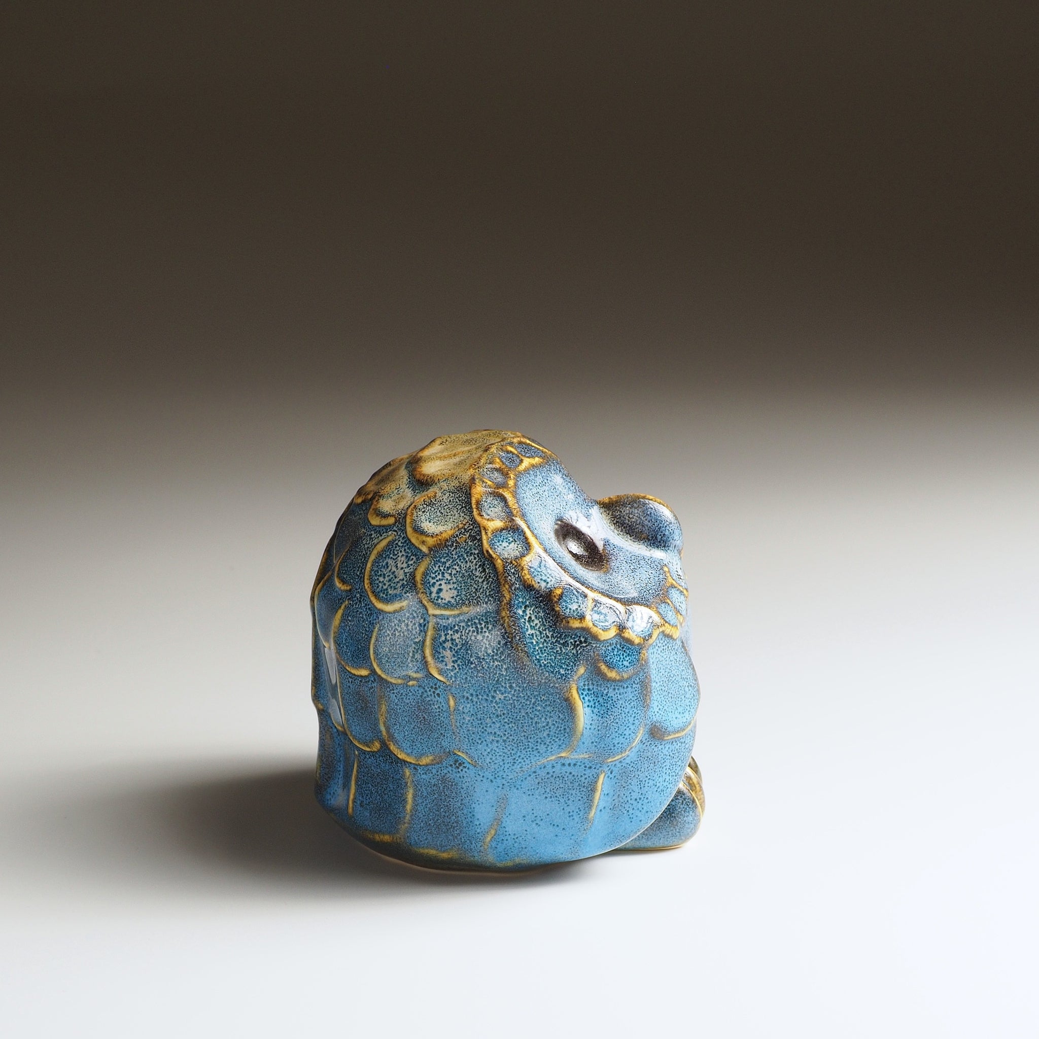 Opposite side view of the small Fukumori ceramic owl ornament with blue glaze and textured gold-edged feathers