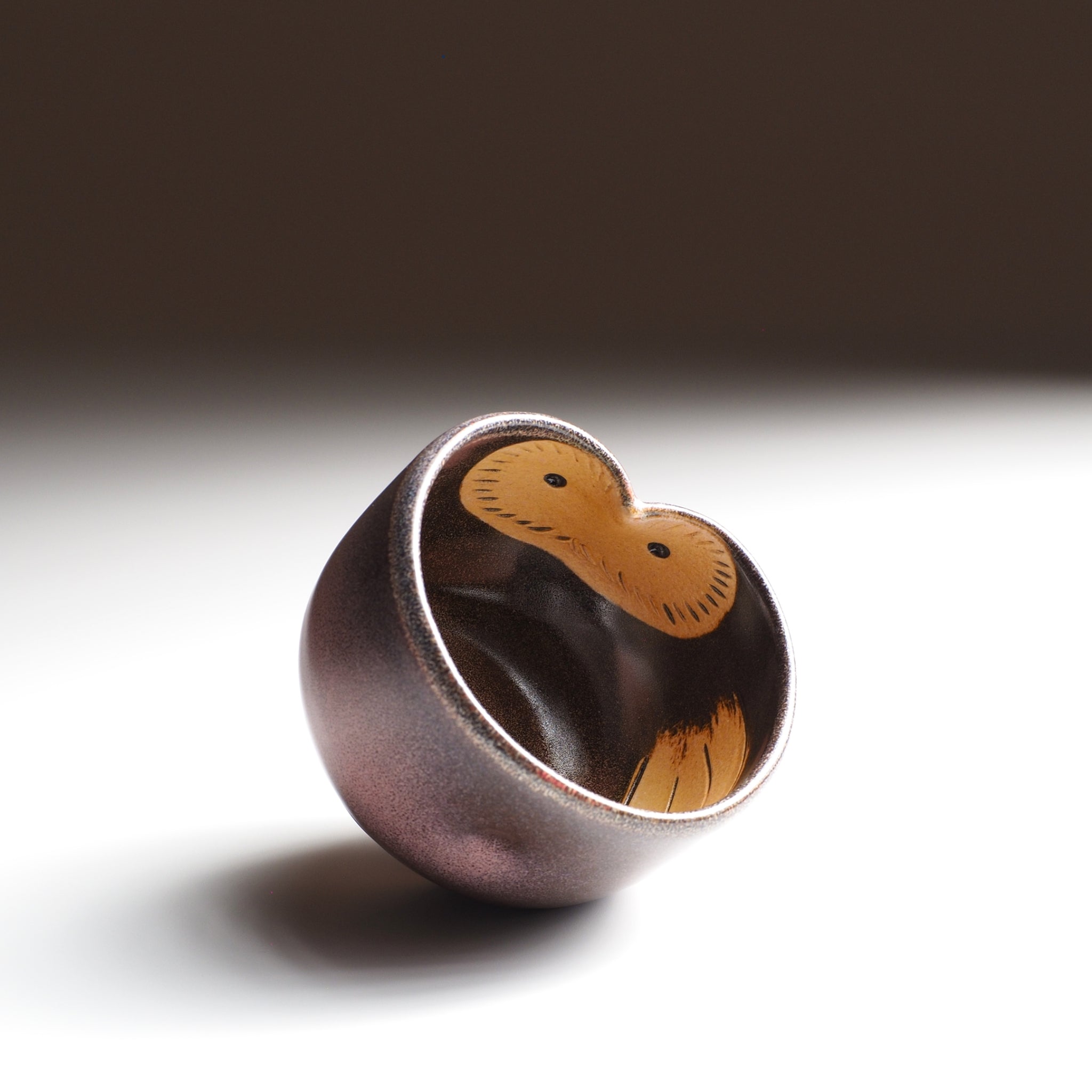 Ceramic Fukuro teacup with owl pattern in a brown and pink interior and exterior on a white background