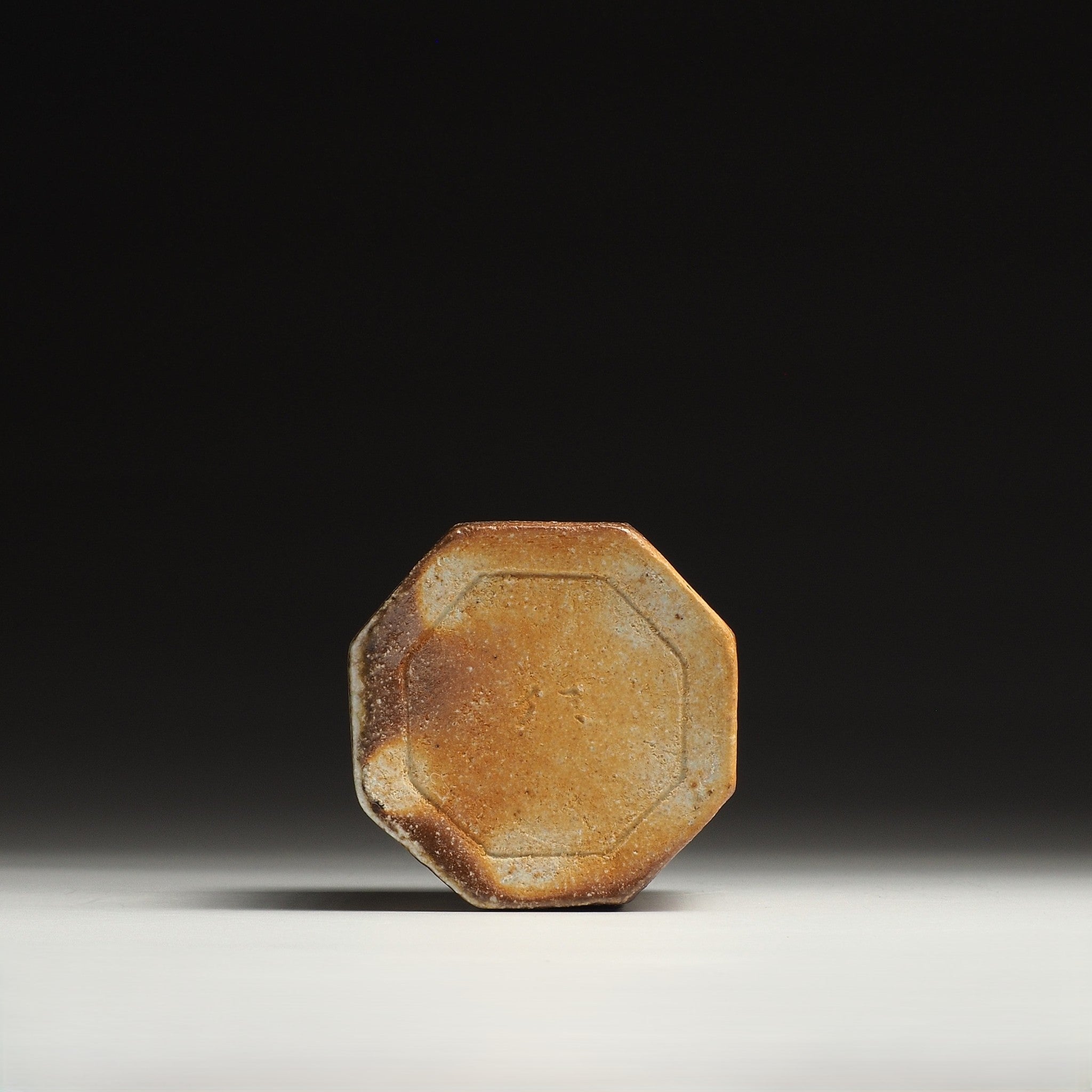 Base view of a Hachiryō Shigaraki cup showing its pale octagonal foot and warm brown firing marks.