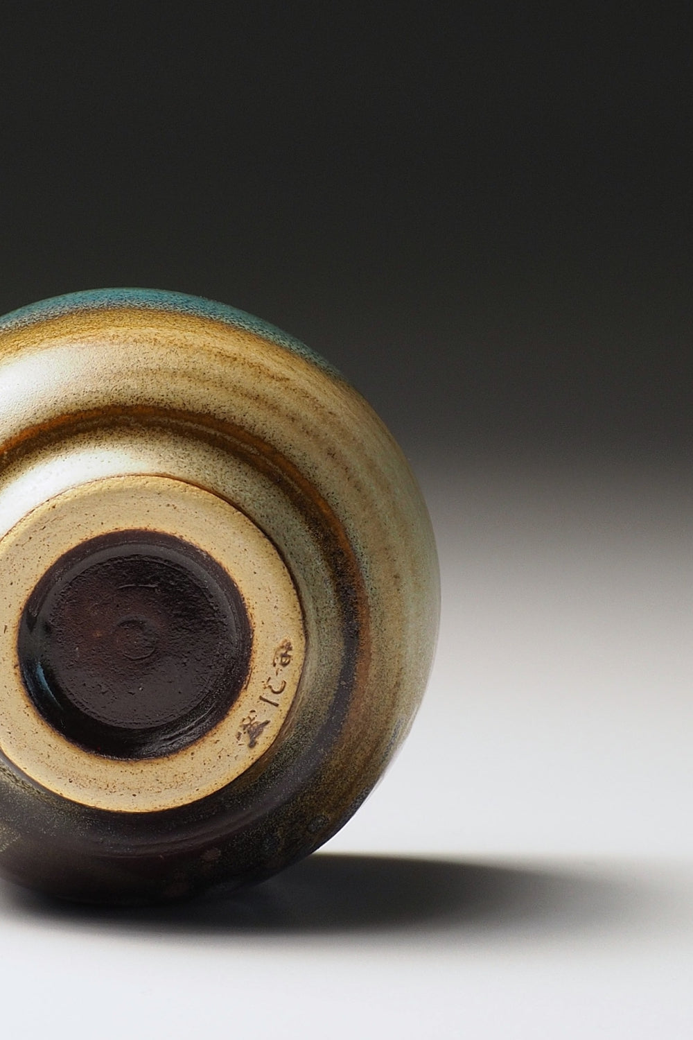 Close-up of the bottom of a guinomi sake cup on a light gray background.