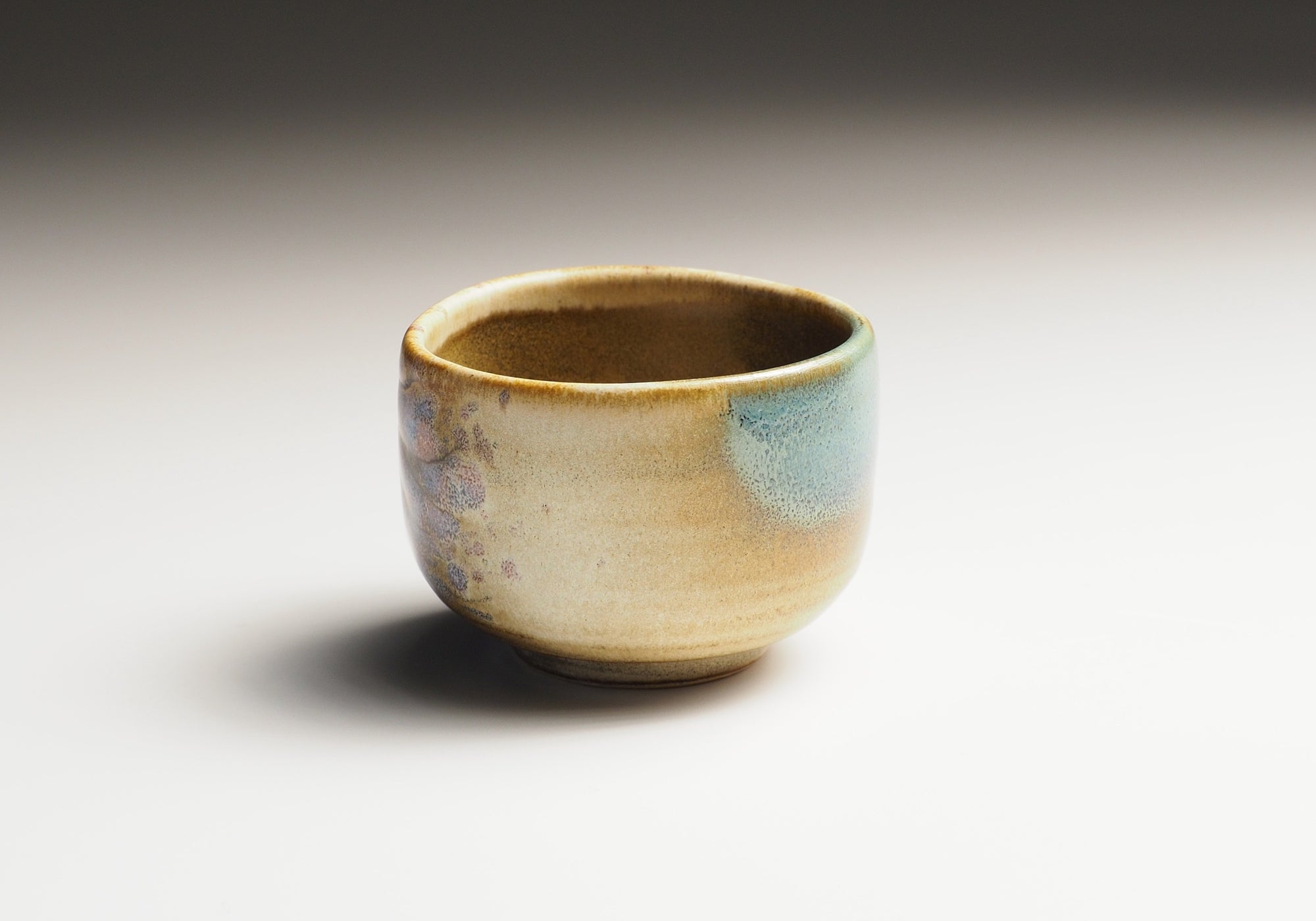Japanese pottery sake cup with a textured surface on a plain background