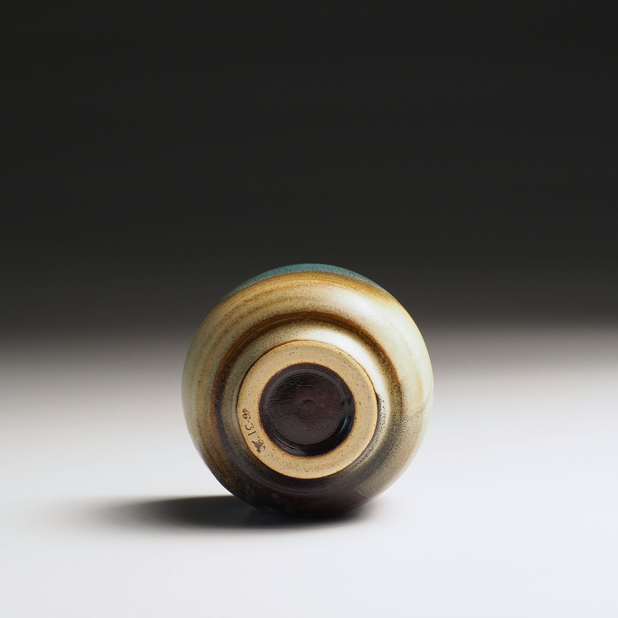 Close-up of a ceramic guinomi sake cup bottom on a gradient background