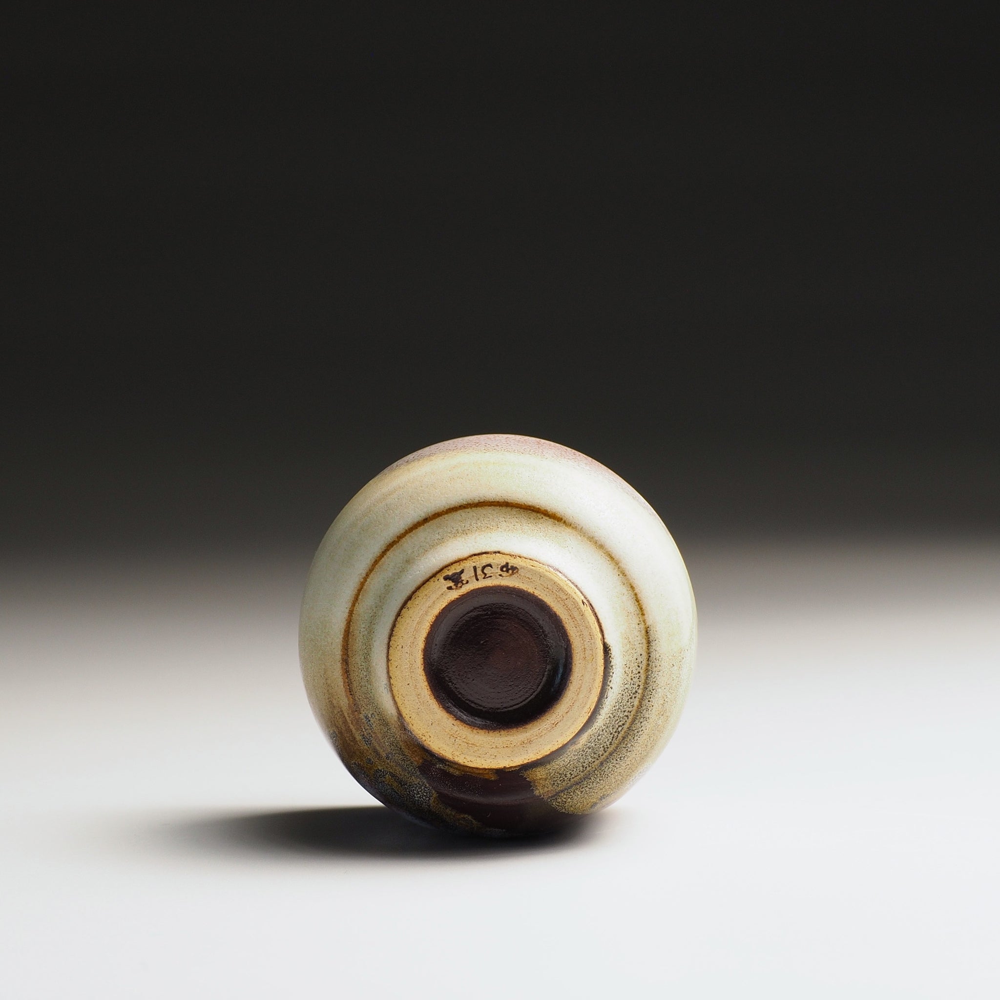Bottom view of a guinomi sake cup on a gradient background