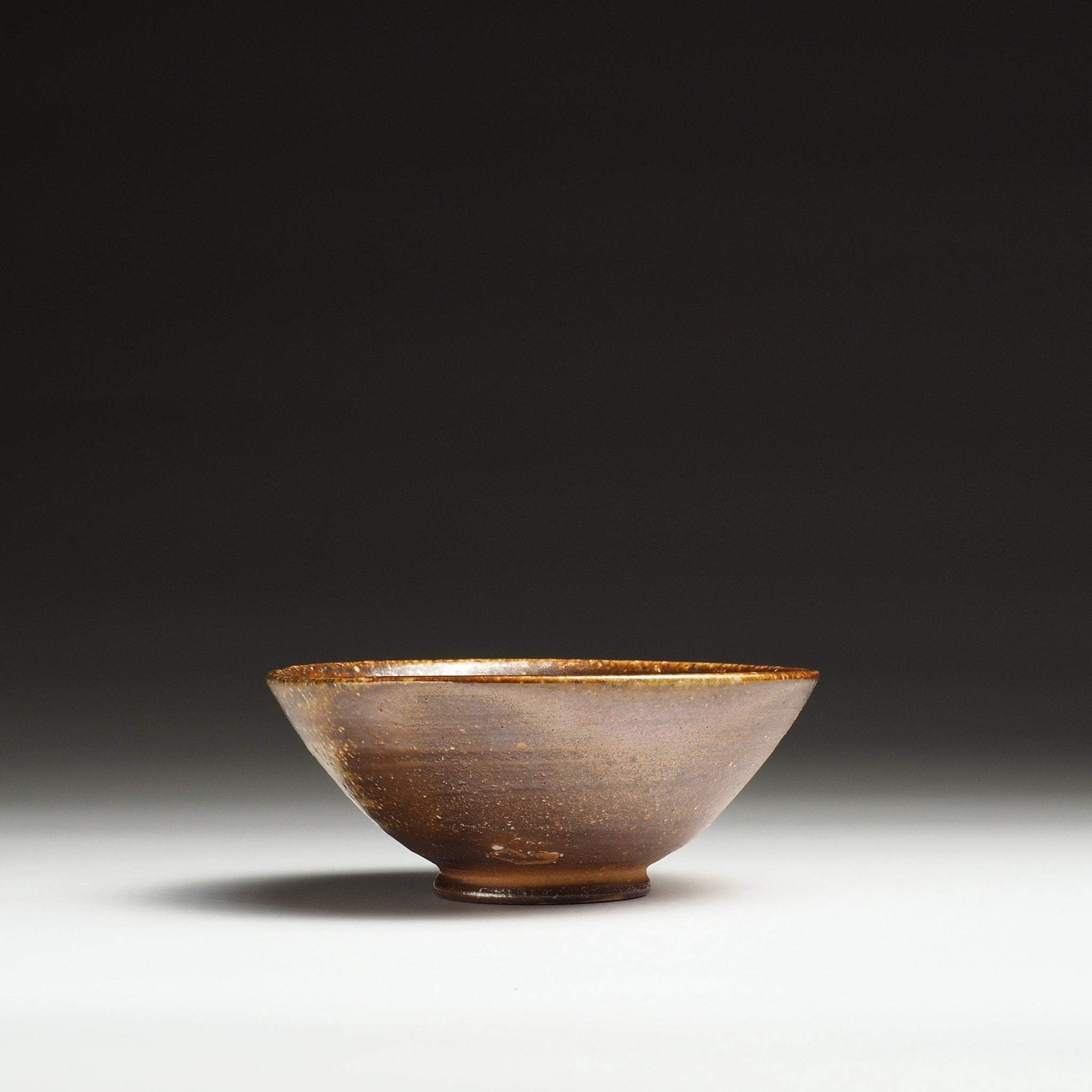 Side view of a Mizuho Shigaraki rice bowl showing its rounded profile and dark brown exterior.