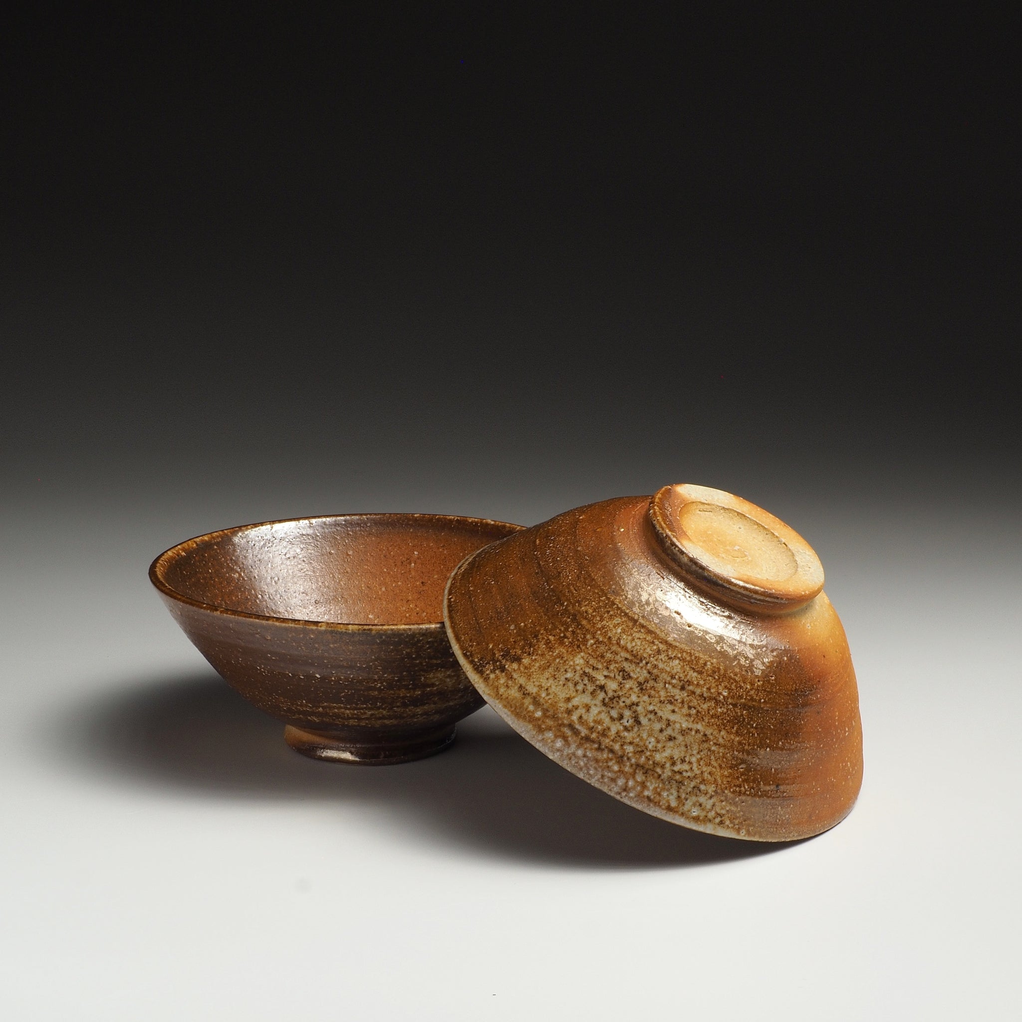 Two Mizuho Shigaraki rice bowls, one upright and one turned to show the foot ring and exterior.