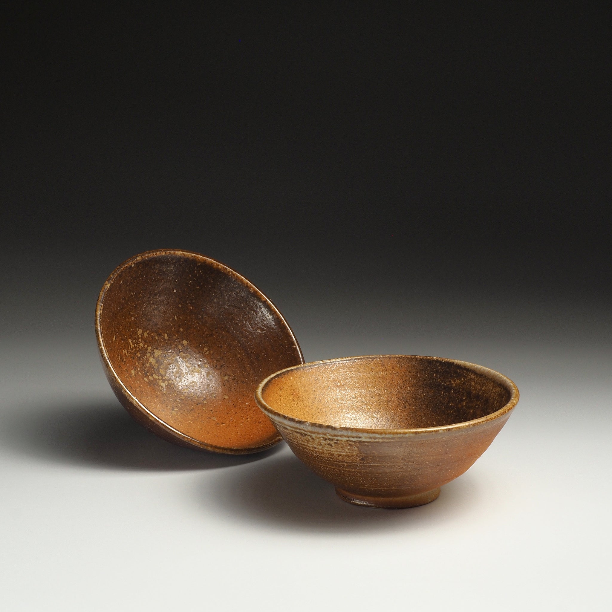 Two Mizuho handmade Shigaraki rice bowls, one upright and one tilted to show the interior.