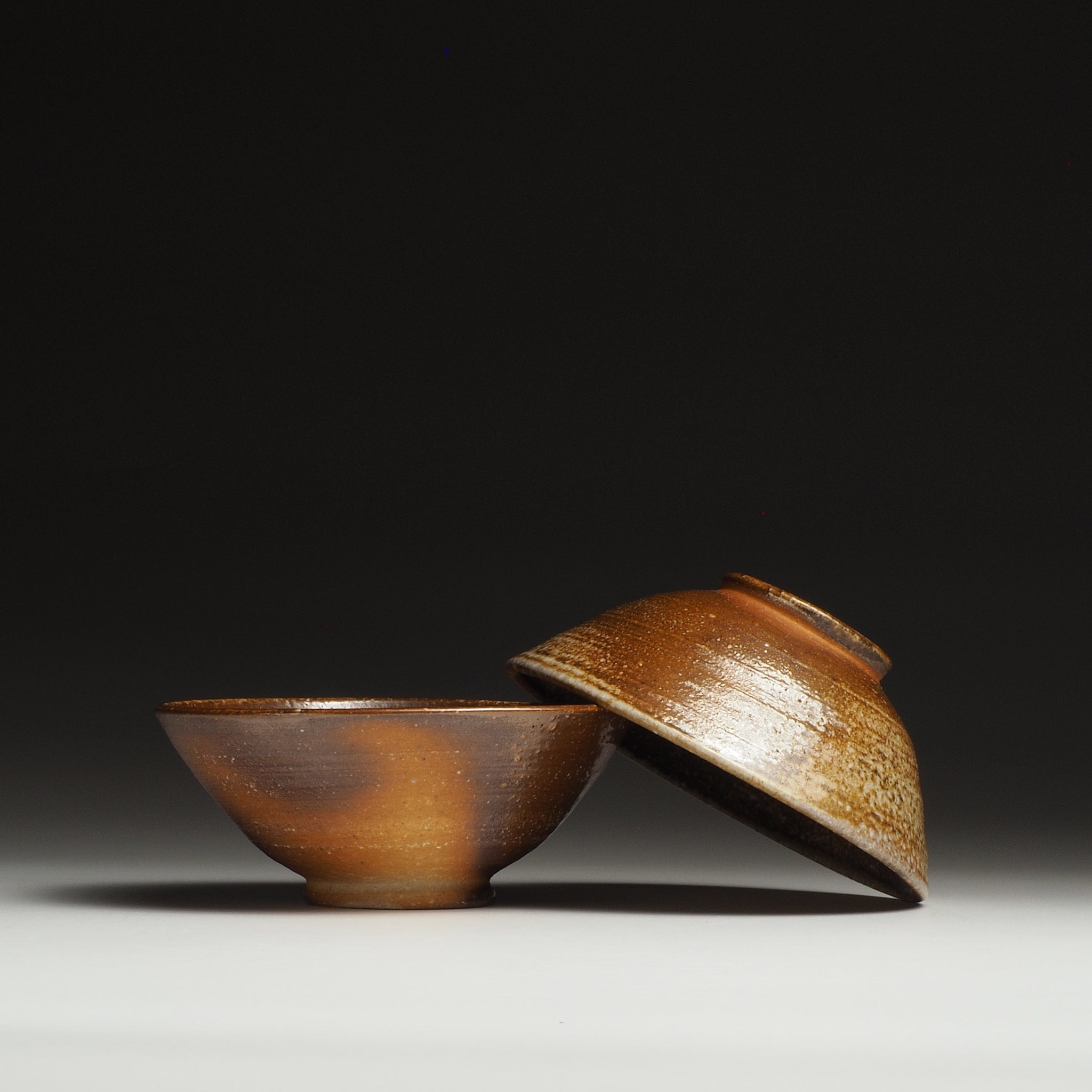 Two Mizuho handmade Shigaraki rice bowls arranged together, with one bowl resting against the other.