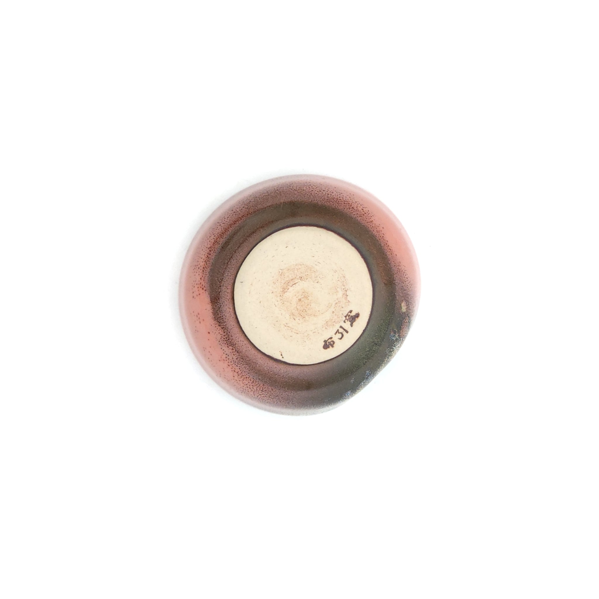 A bottom view of a pink Japanese round sake cup. Tsukushi